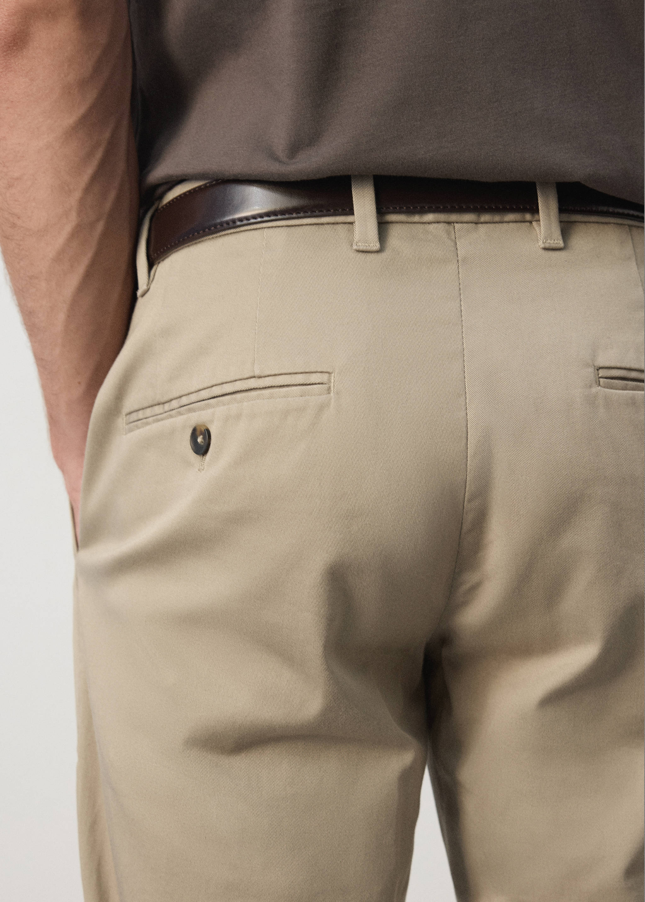 Beige trousers featuring belt loops and a single-welt back button pocket.