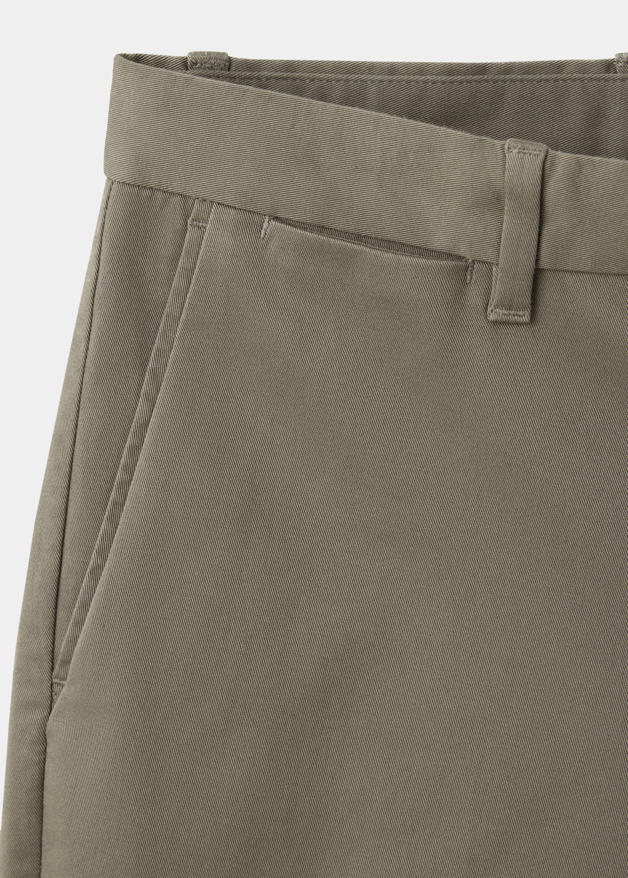 Khaki green men's trousers detail focusing on the waistband and pocket.