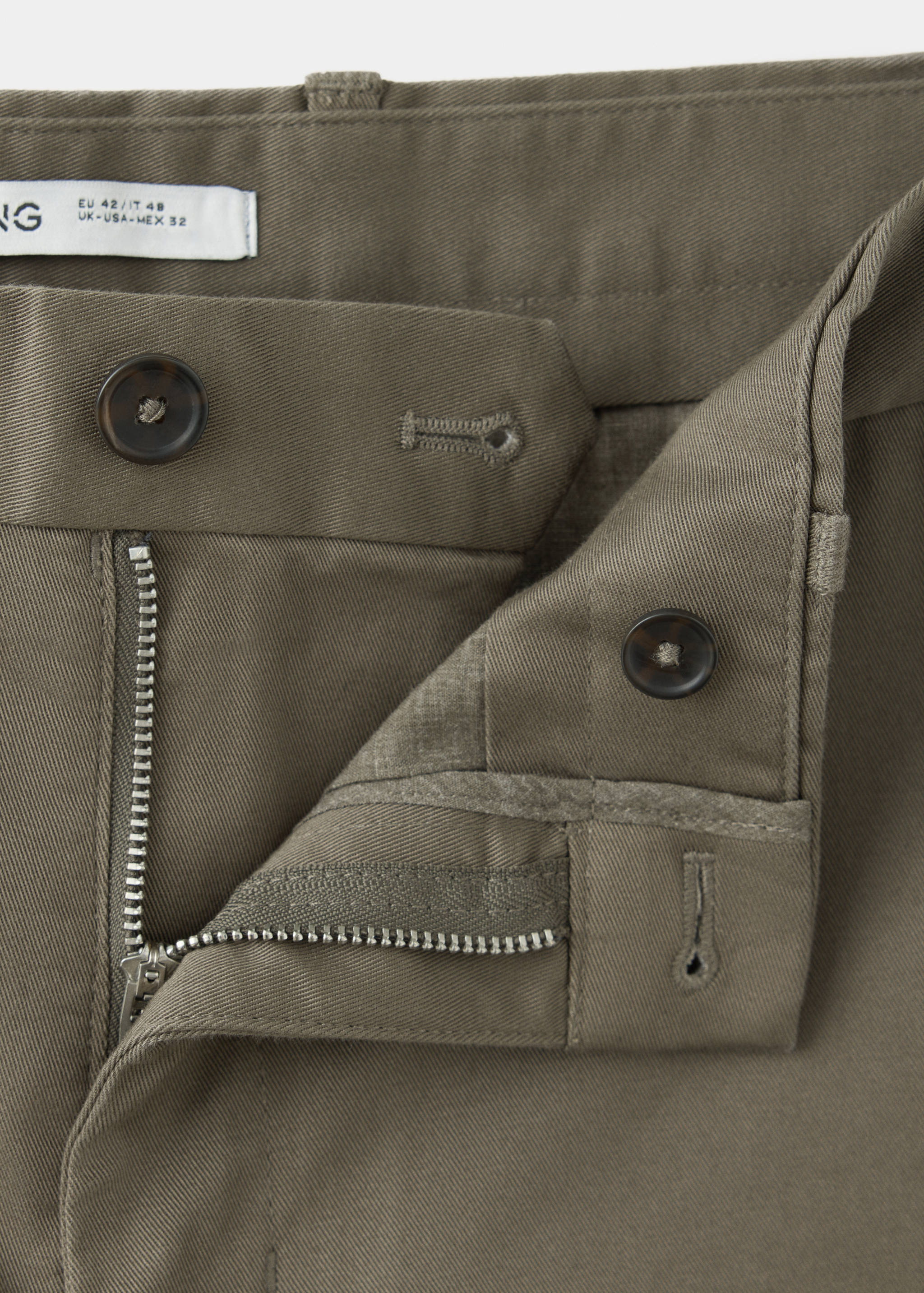 Close-up of khaki green trousers, focusing on the waistband and fastening.
