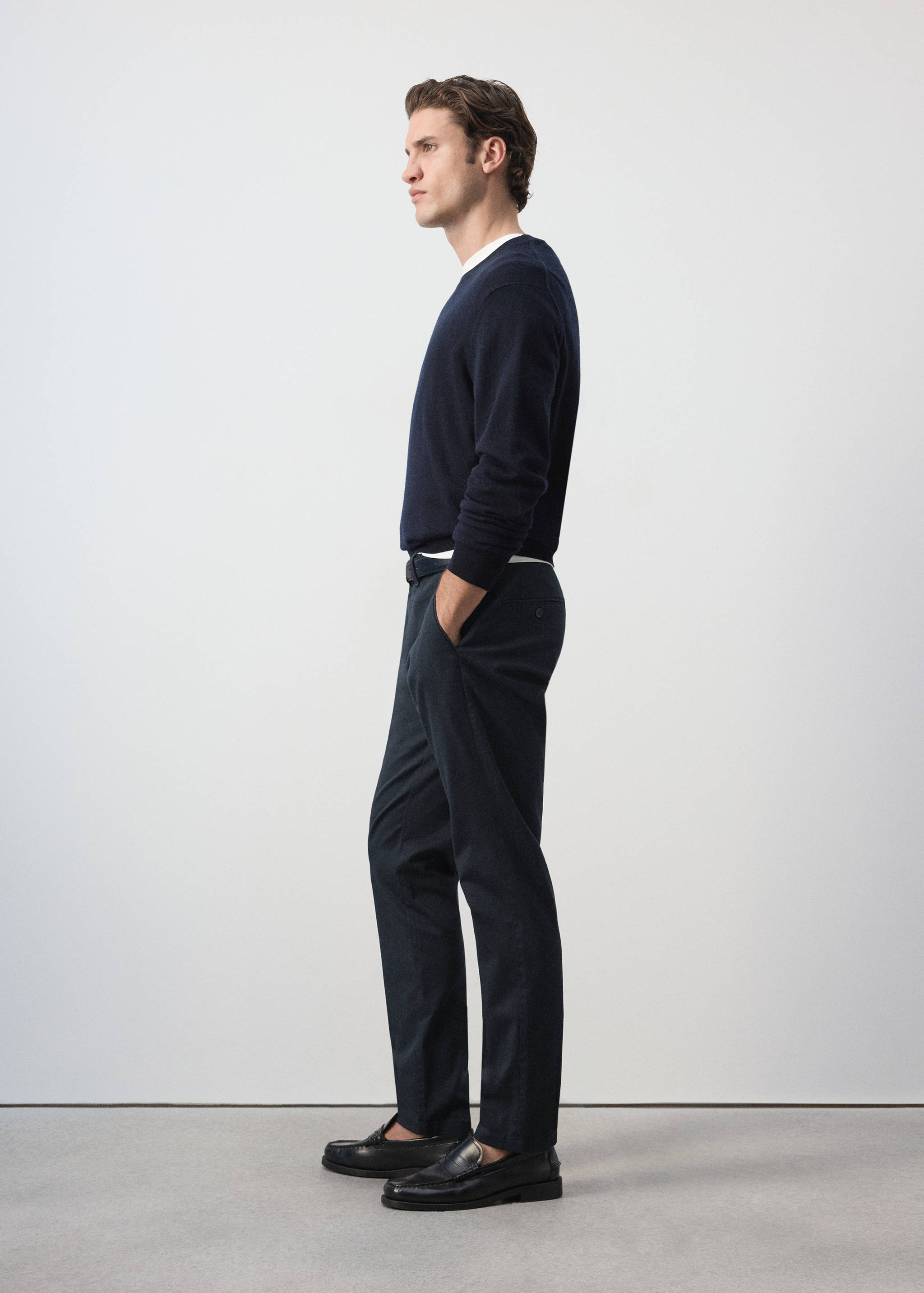 Dark trousers with a straight fit, worn with a dark blue jumper.