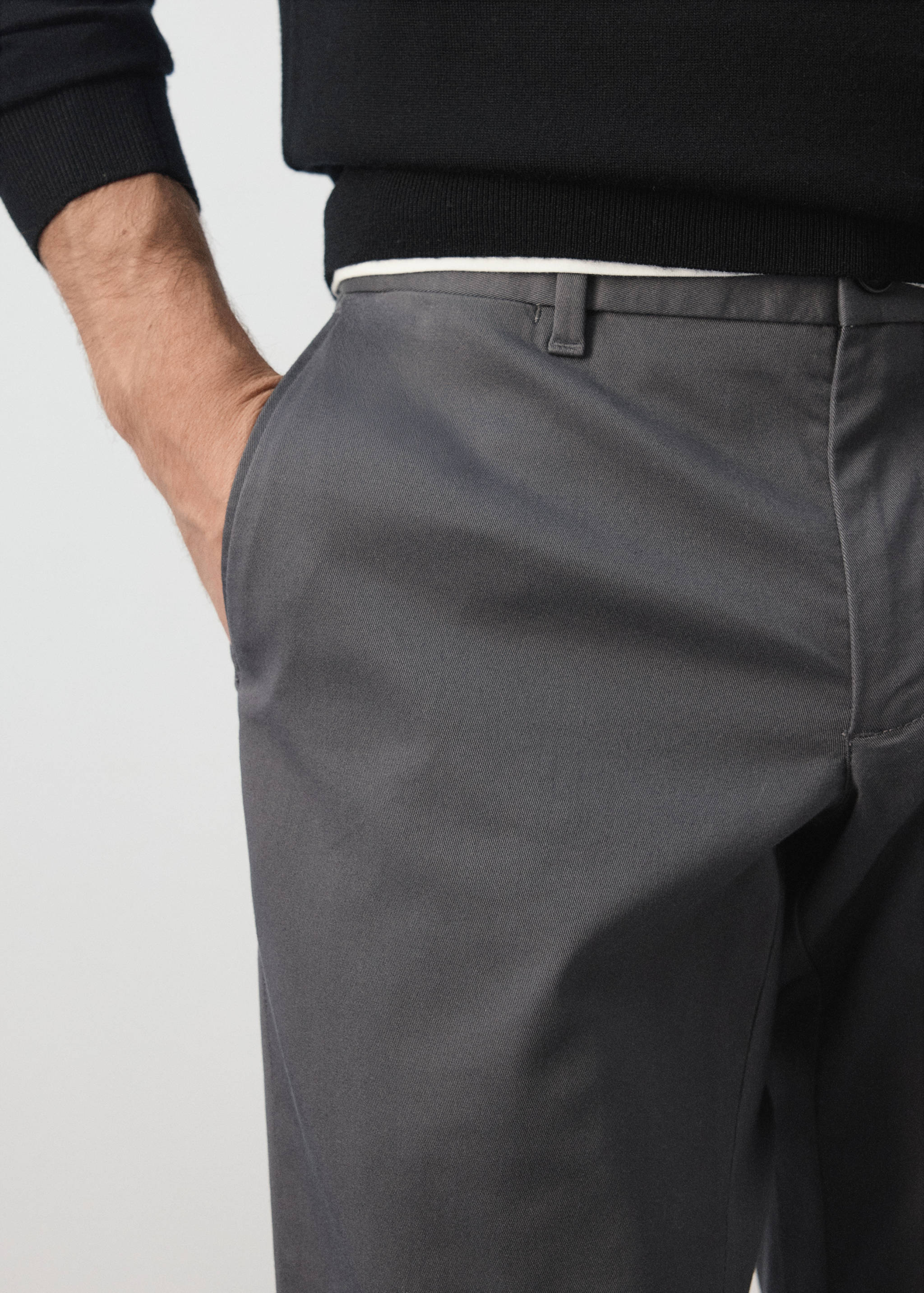 Dark grey trousers with belt loops and side pockets.