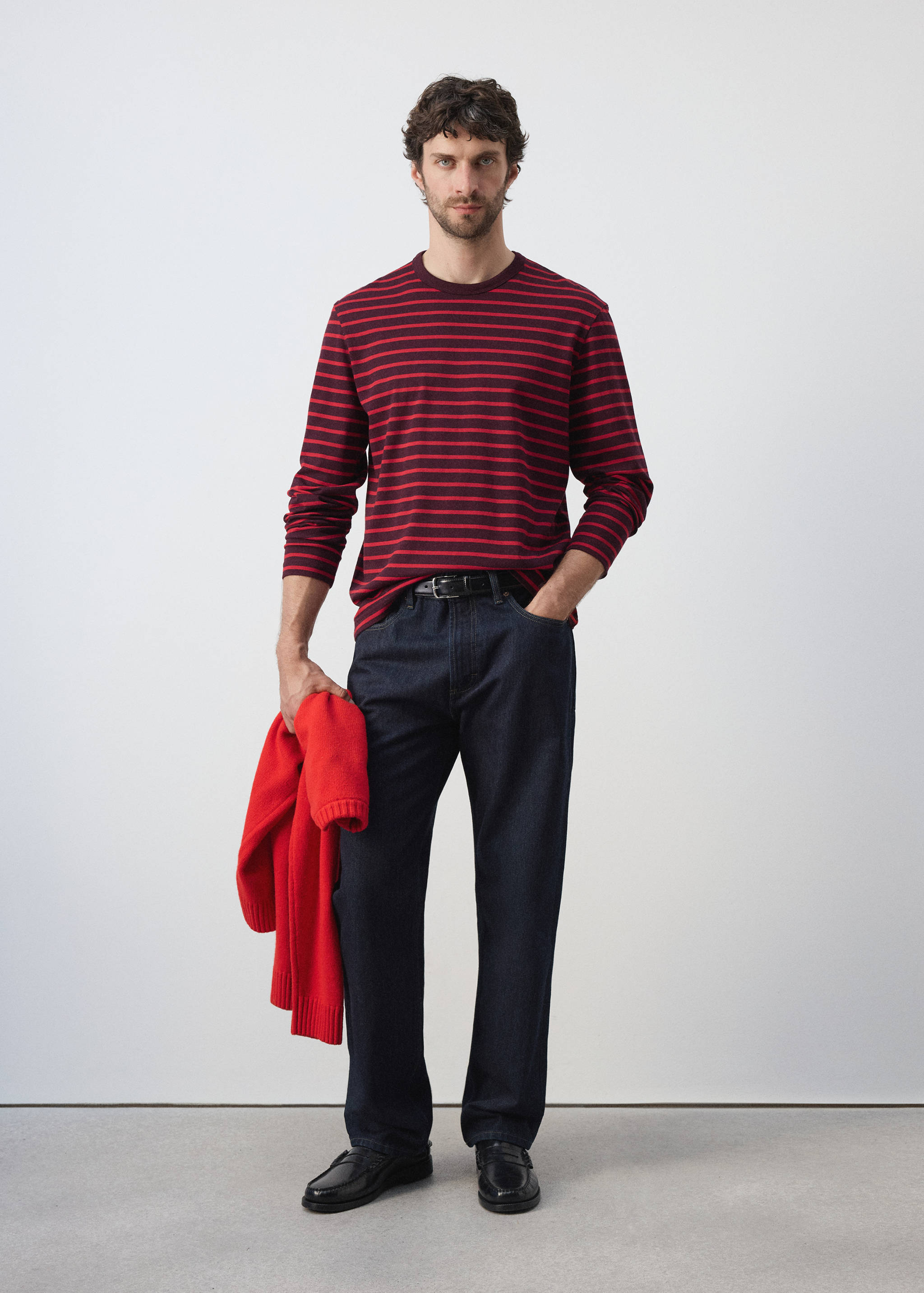 Red and dark striped long-sleeved t-shirt worn with dark blue jeans.
