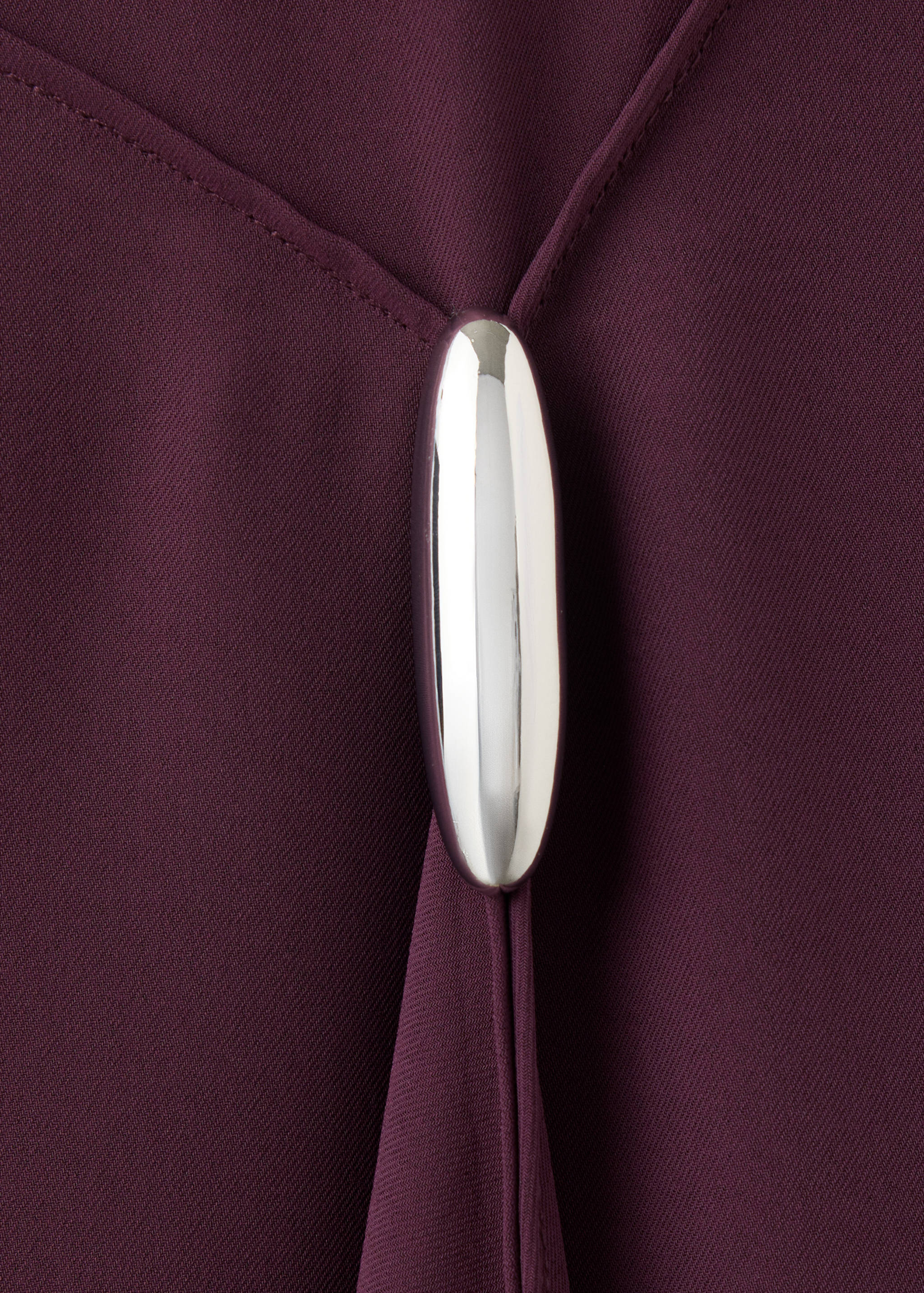 Close-up of burgundy dress fabric with metallic silver hardware detail.