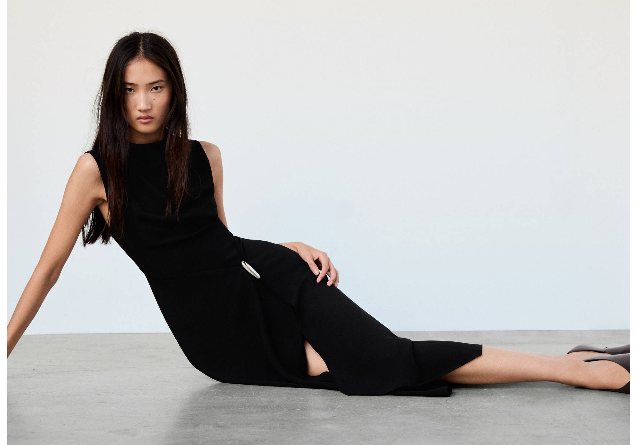 Black sleeveless midi dress with a high neck and a metallic waist buckle.