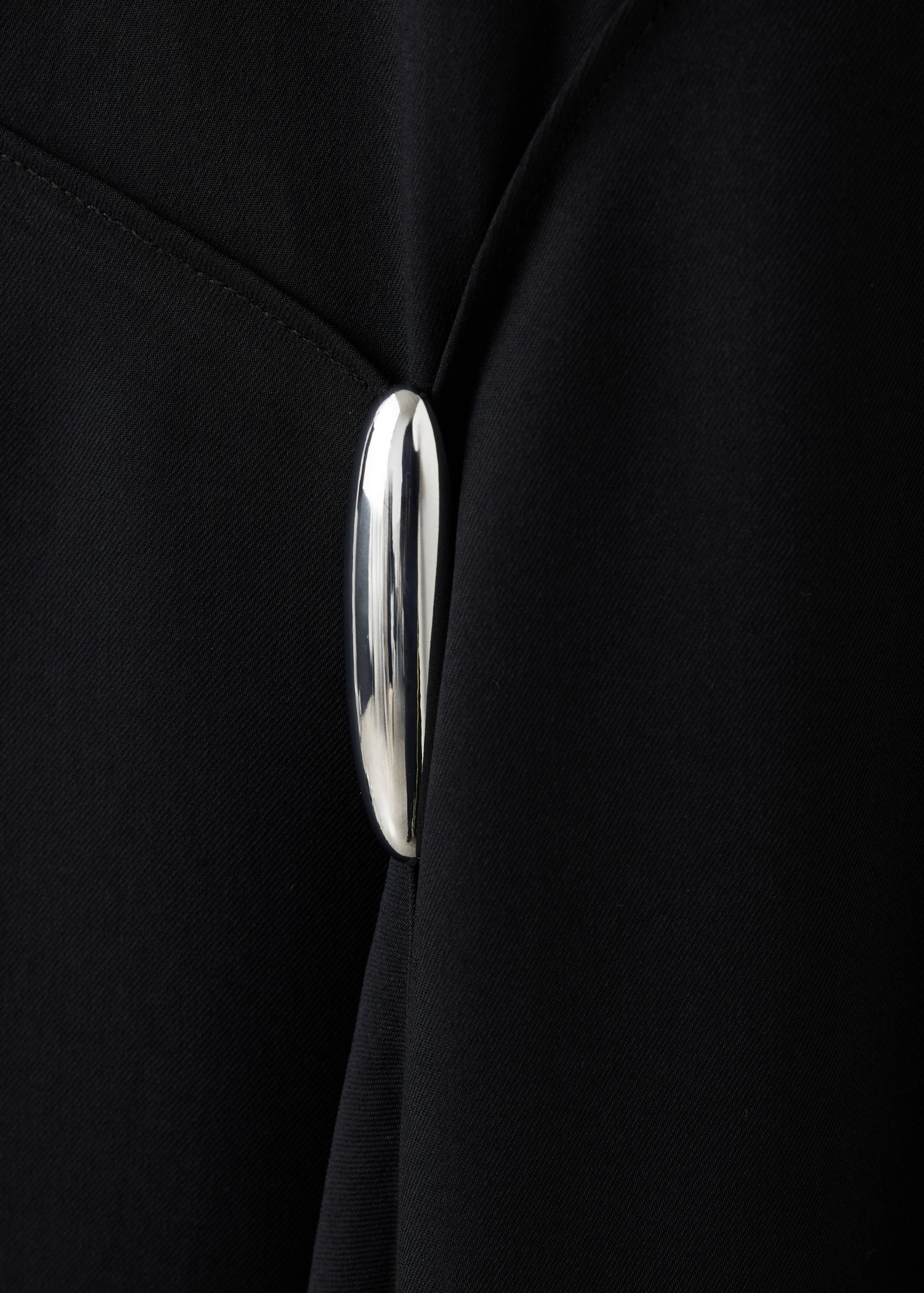 Black dress detail showing a shiny silver-tone clasp.