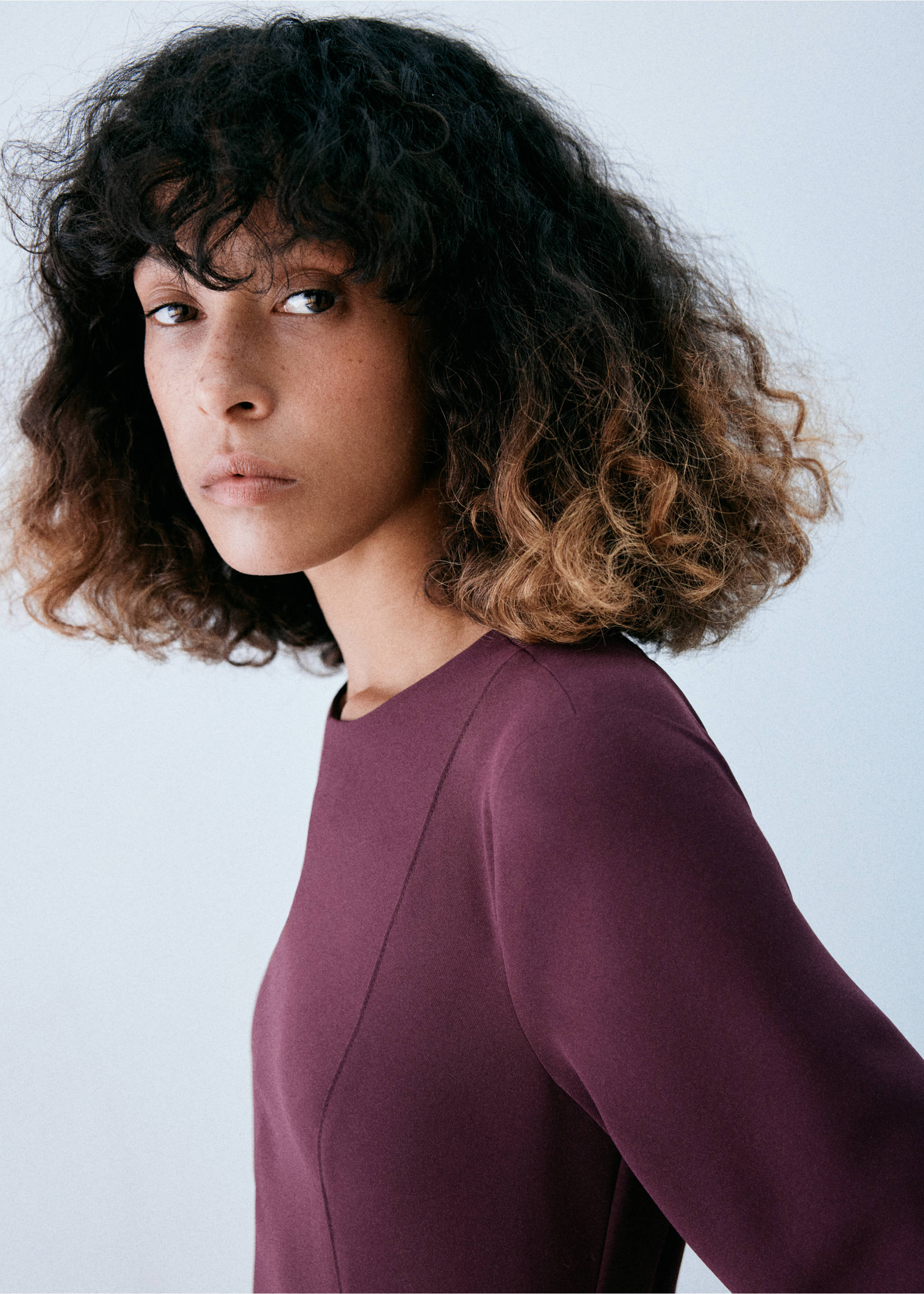 Close-up of a model wearing a burgundy dress with a rounded neckline., Burgundy. Ref: 47071445-00.
