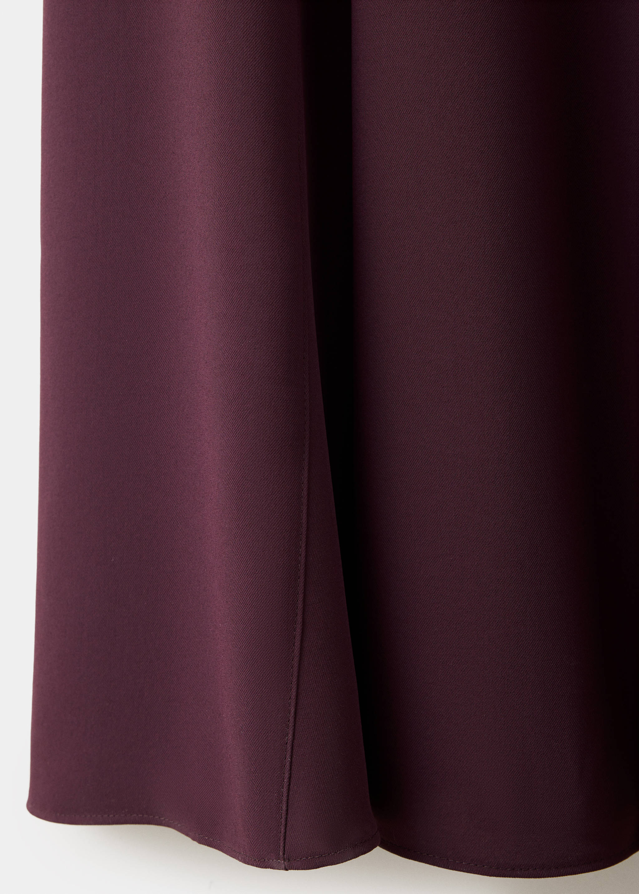 Burgundy dress detail showing smooth fabric texture and drape.