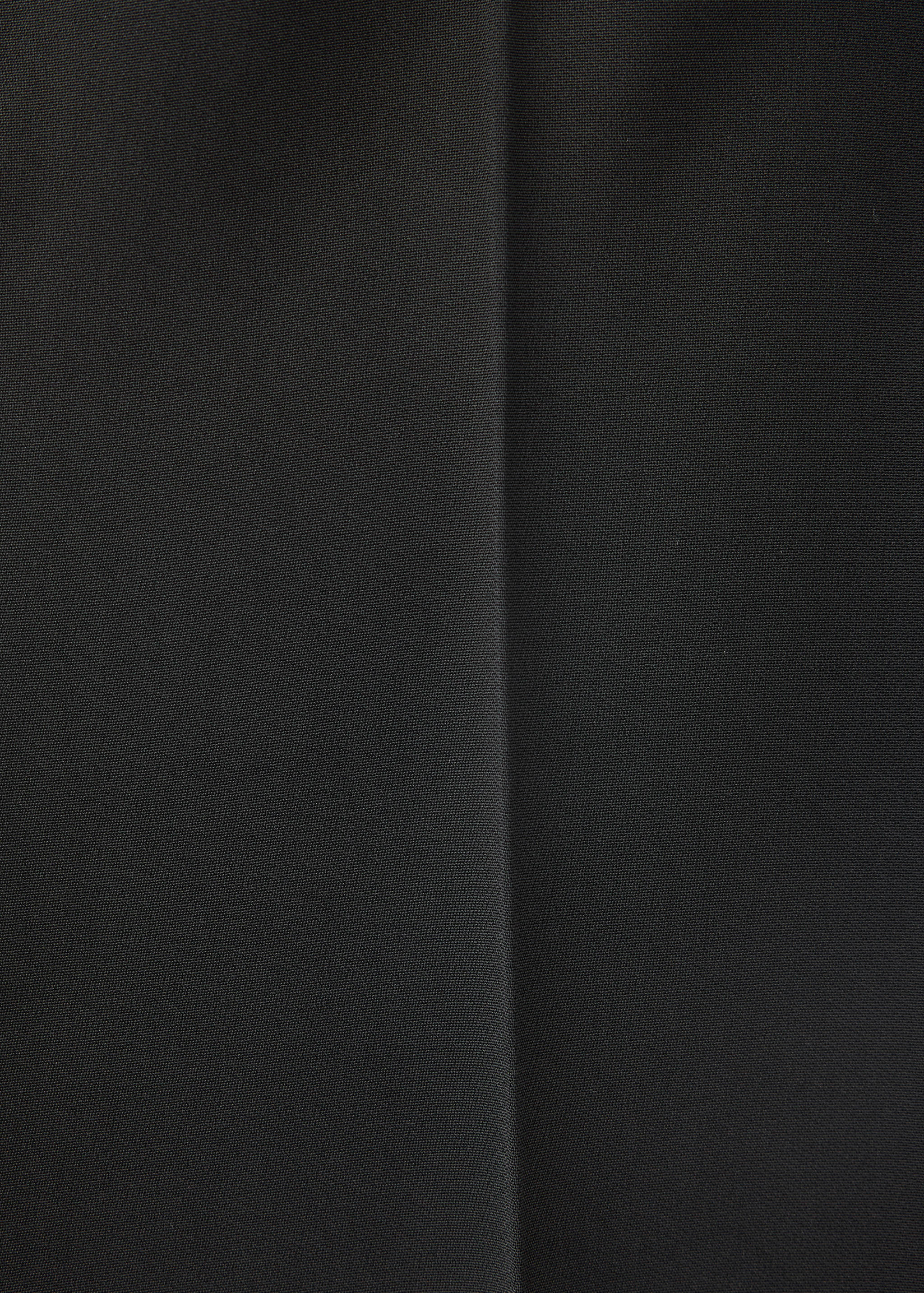 Primer plano de pantalones negros con detalle de raya marcada.