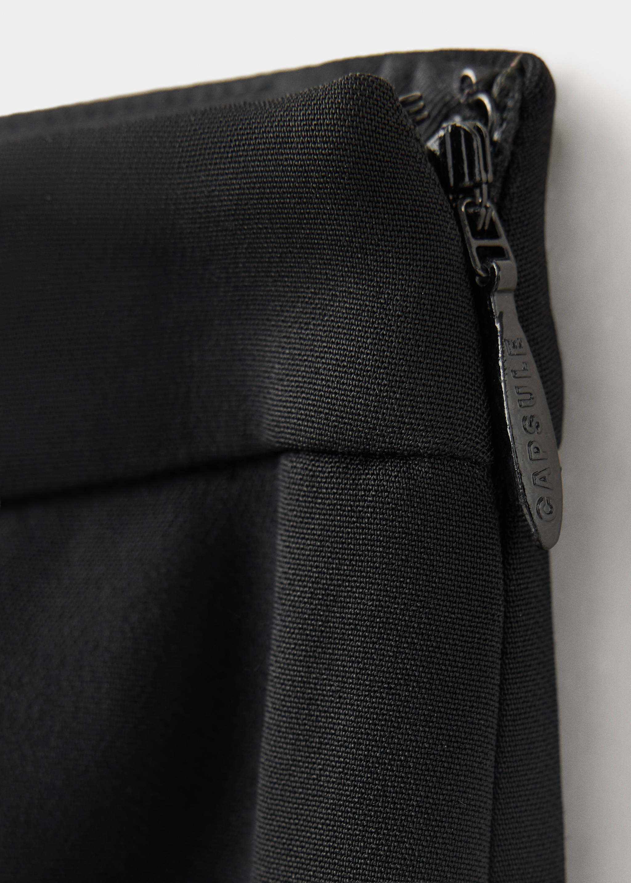 Pantalones negros con detalle de tejido y cremallera lateral.
