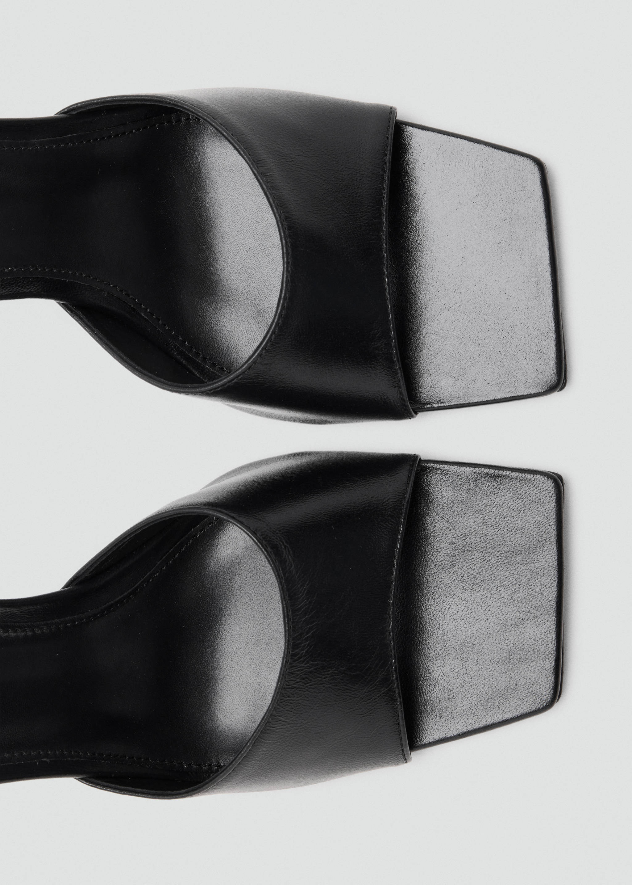 Close-up of black sandals with a square toe design.