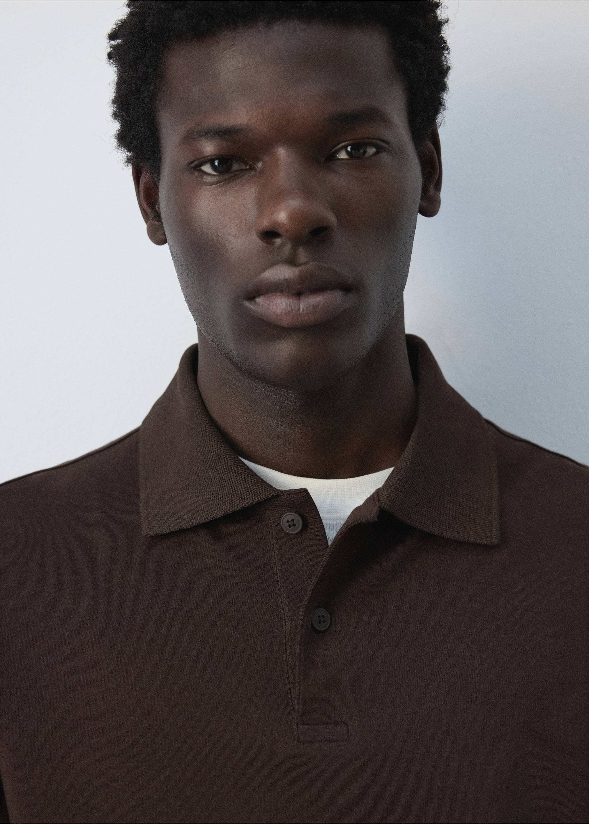 Close-up of a dark brown polo shirt with a collar and button placket., Chocolate. Ref: 47081410-00.