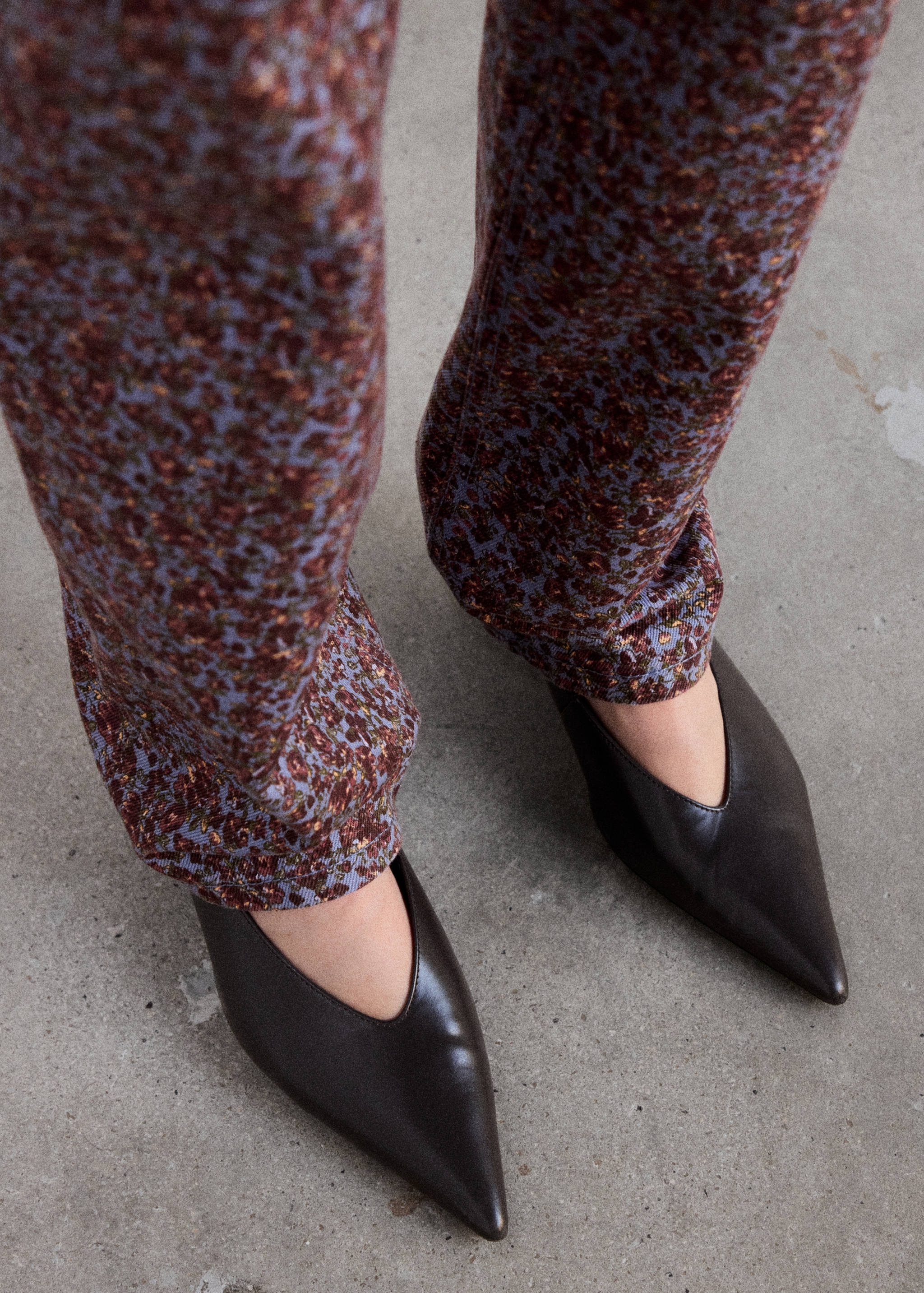 Blue floral denim trousers paired with dark brown pointed-toe shoes.