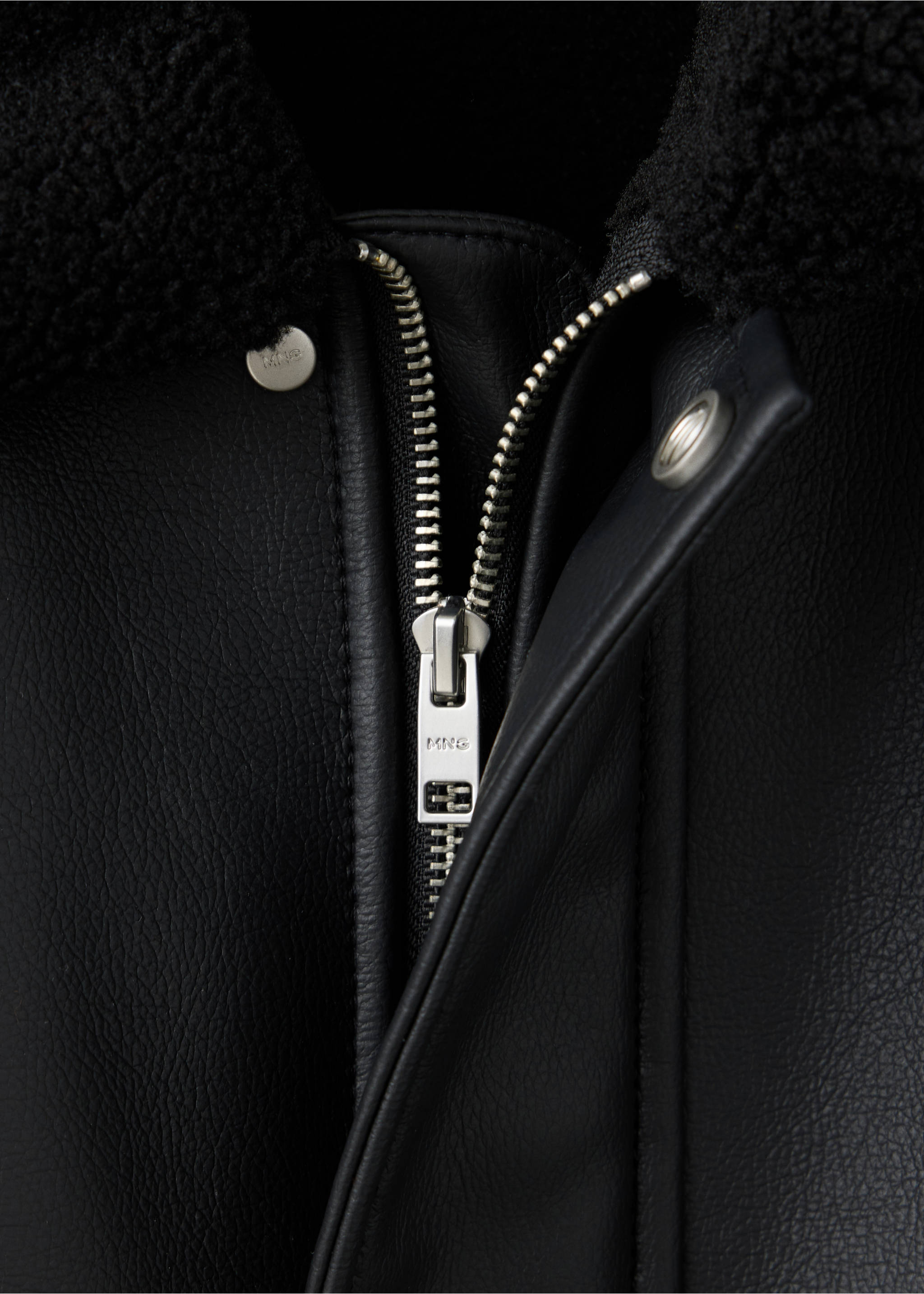 Close-up of a black men's jacket with a faux-shearling collar and silver metal zip detail., Black. Ref: 47091329-00.