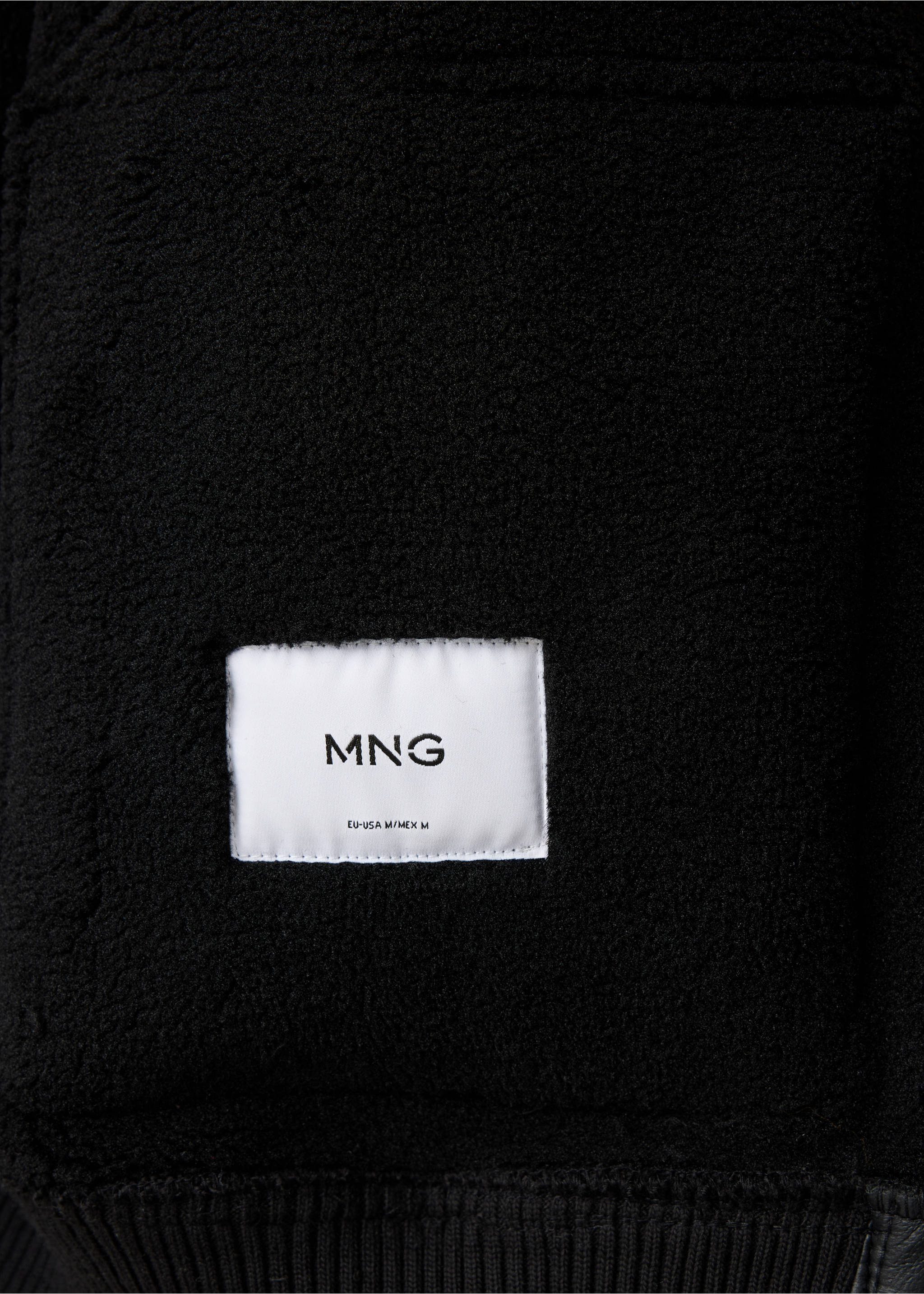 Close-up of black jacket interior with faux-shearling lining and MNG label., Black. Ref: 47091329-00.