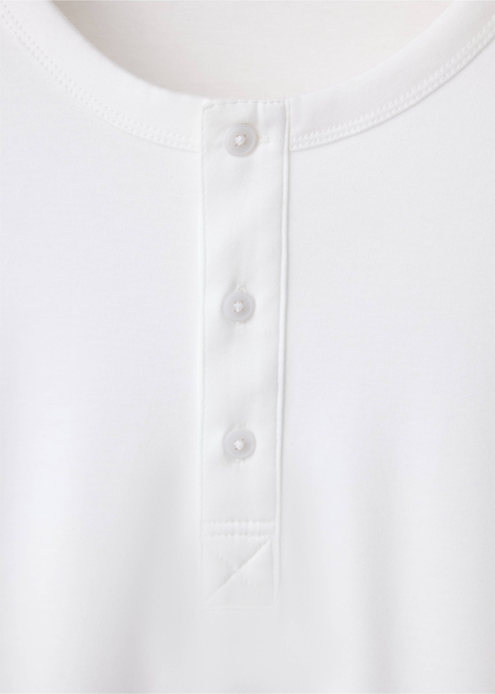 Detalle de camiseta blanca que muestra un cuello redondo y una tapeta de botones., Blanco. Ref: 47091350-00.