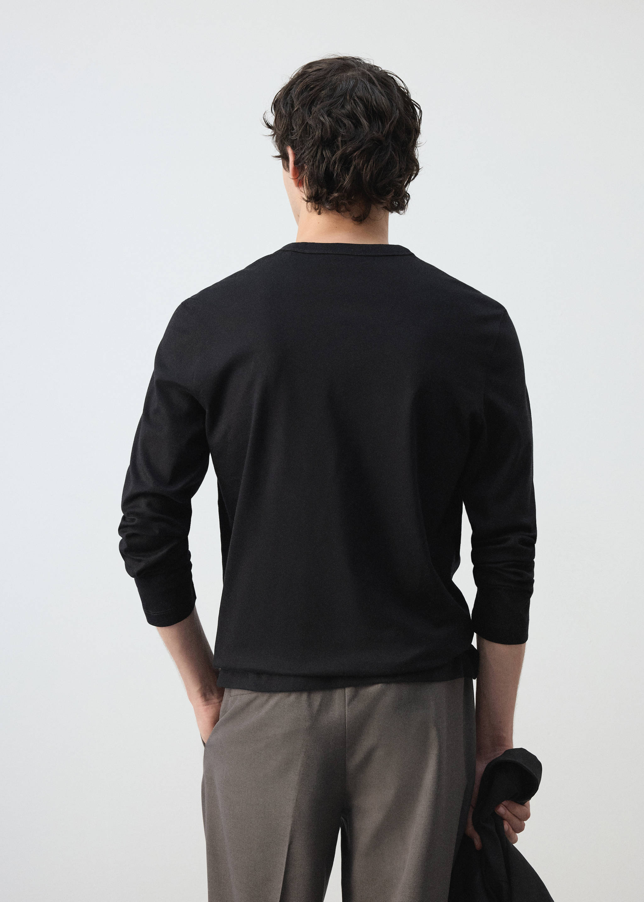 Vista trasera de camiseta lisa de manga larga negra con cuello redondo.