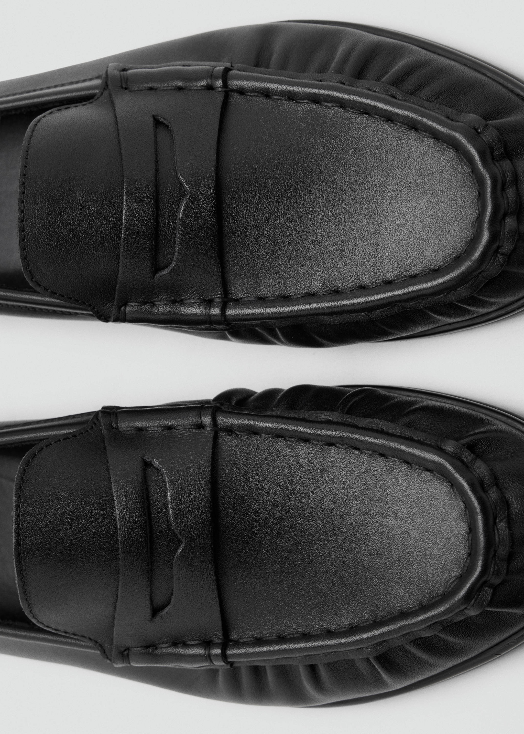 Close-up of black leather loafers with traditional strap detail.