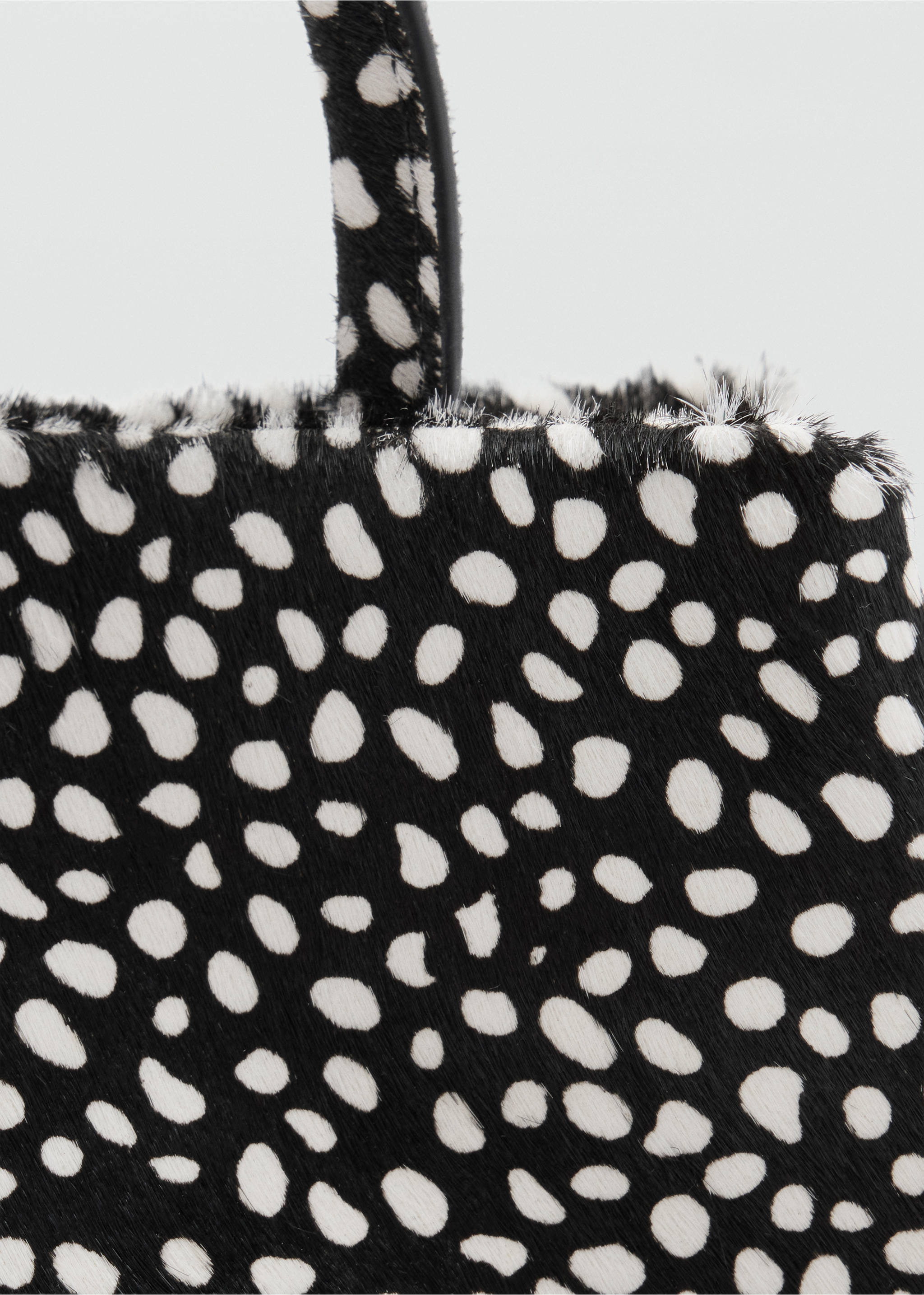 Black and white animal spot handbag detail with a textured finish., Black. Ref: 47091375-00.