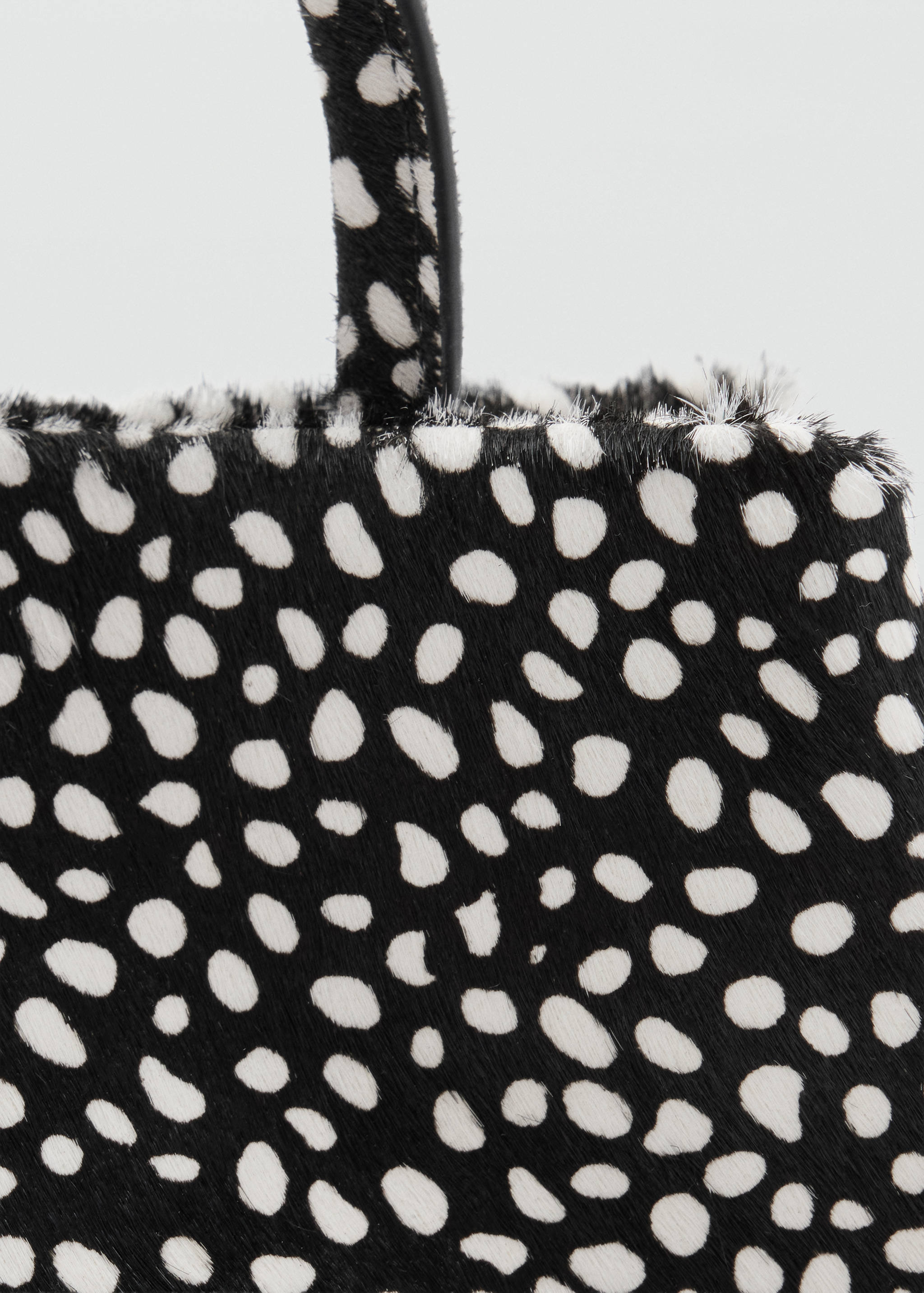 Black and white animal spot handbag detail with a textured finish.
