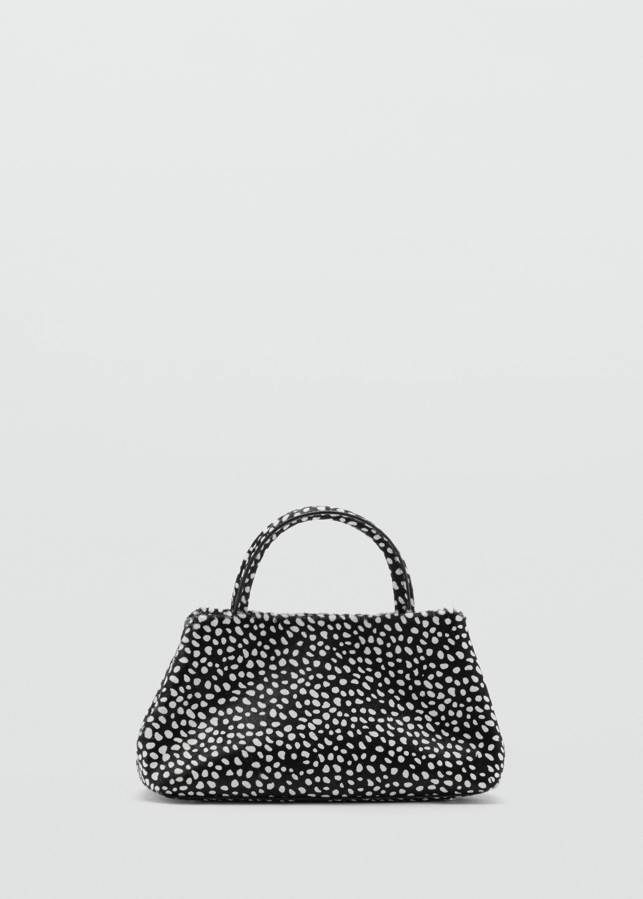 Black and white faux-fur handbag with a dalmatian print and top handle.