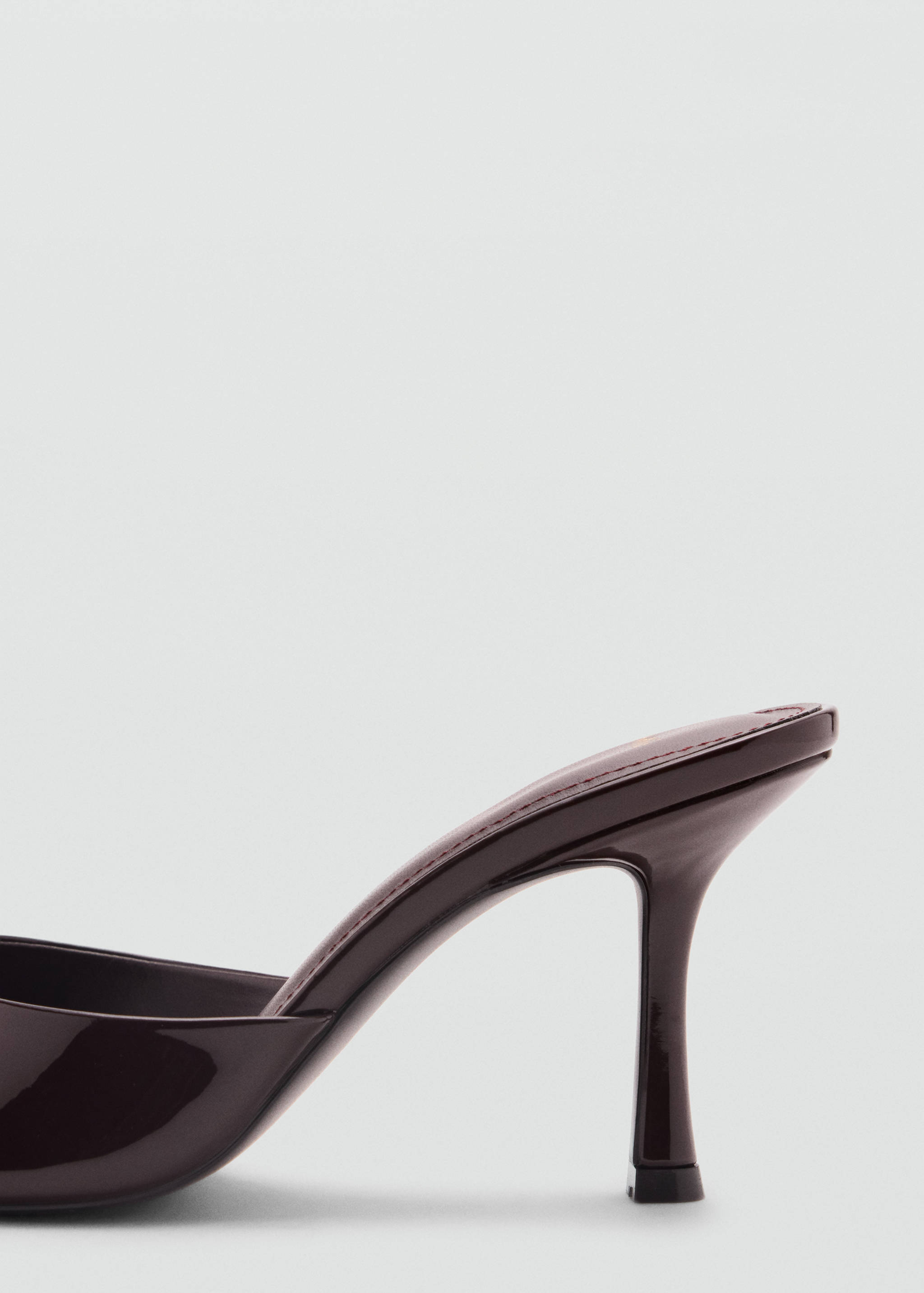 Close-up of a dark burgundy patent heel sandal showing the side profile and slim stiletto heel.