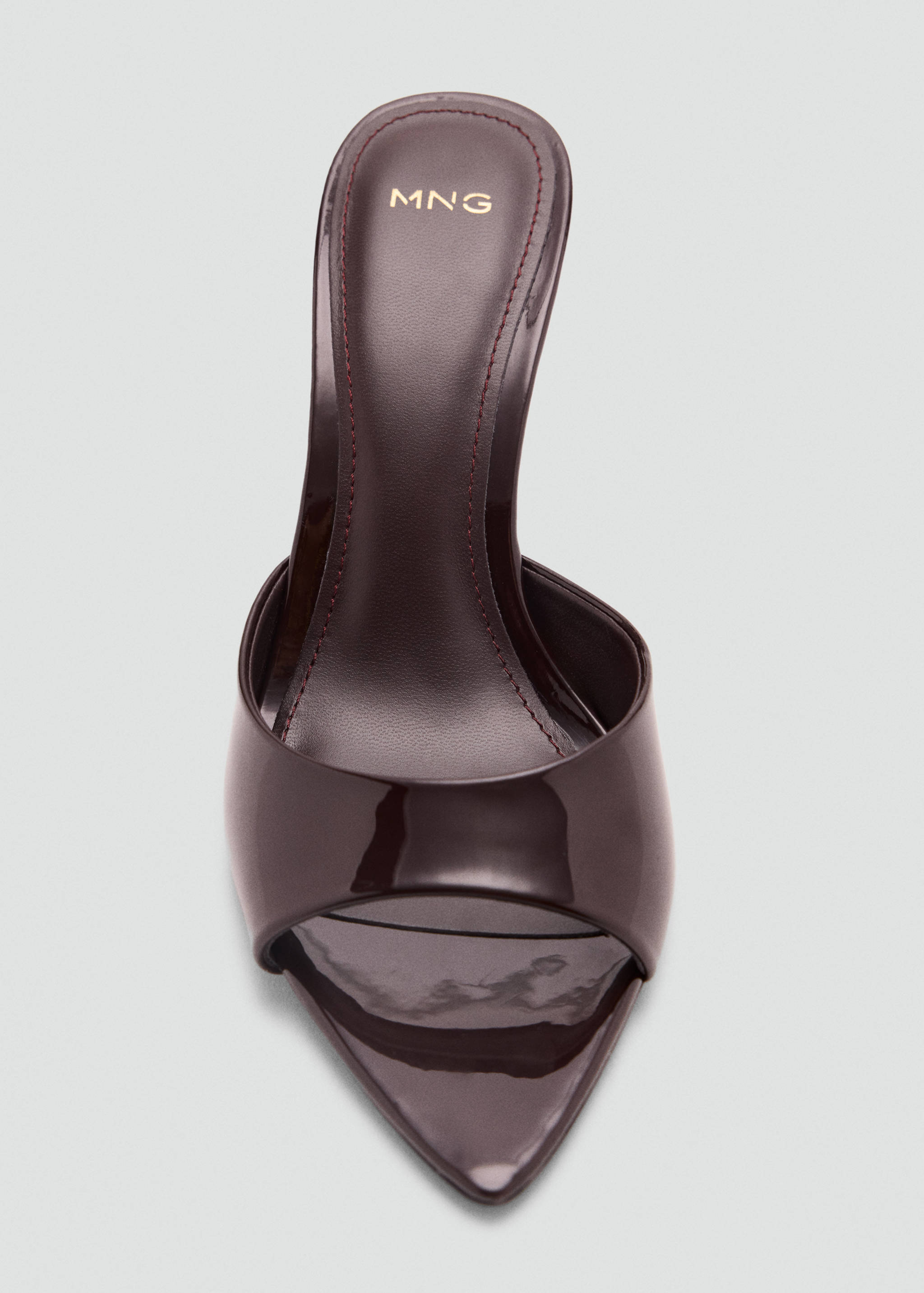 Close-up of a dark burgundy patent leather mule sandal with an open pointed toe.