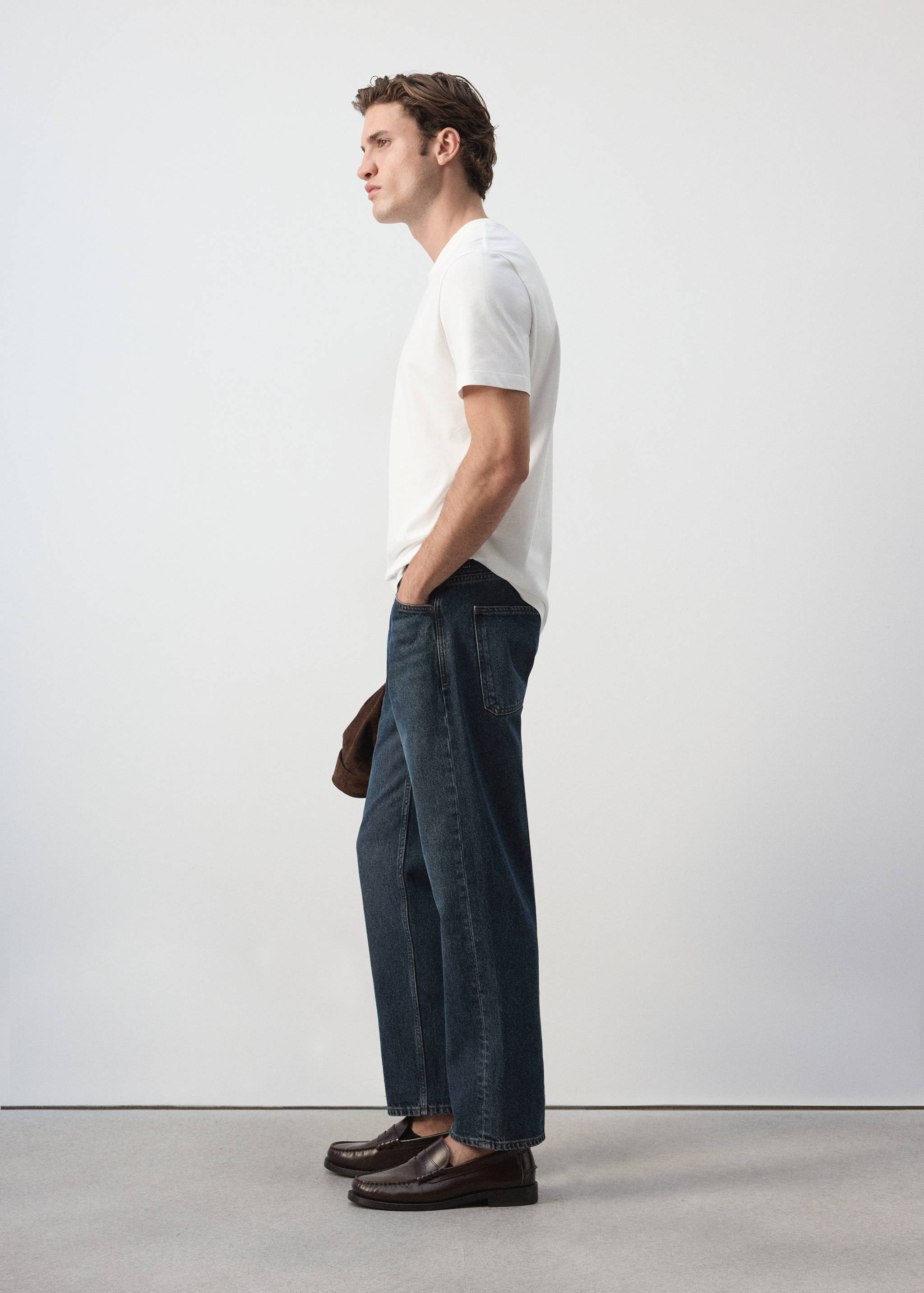 White short-sleeved t-shirt worn with dark blue denim trousers.
