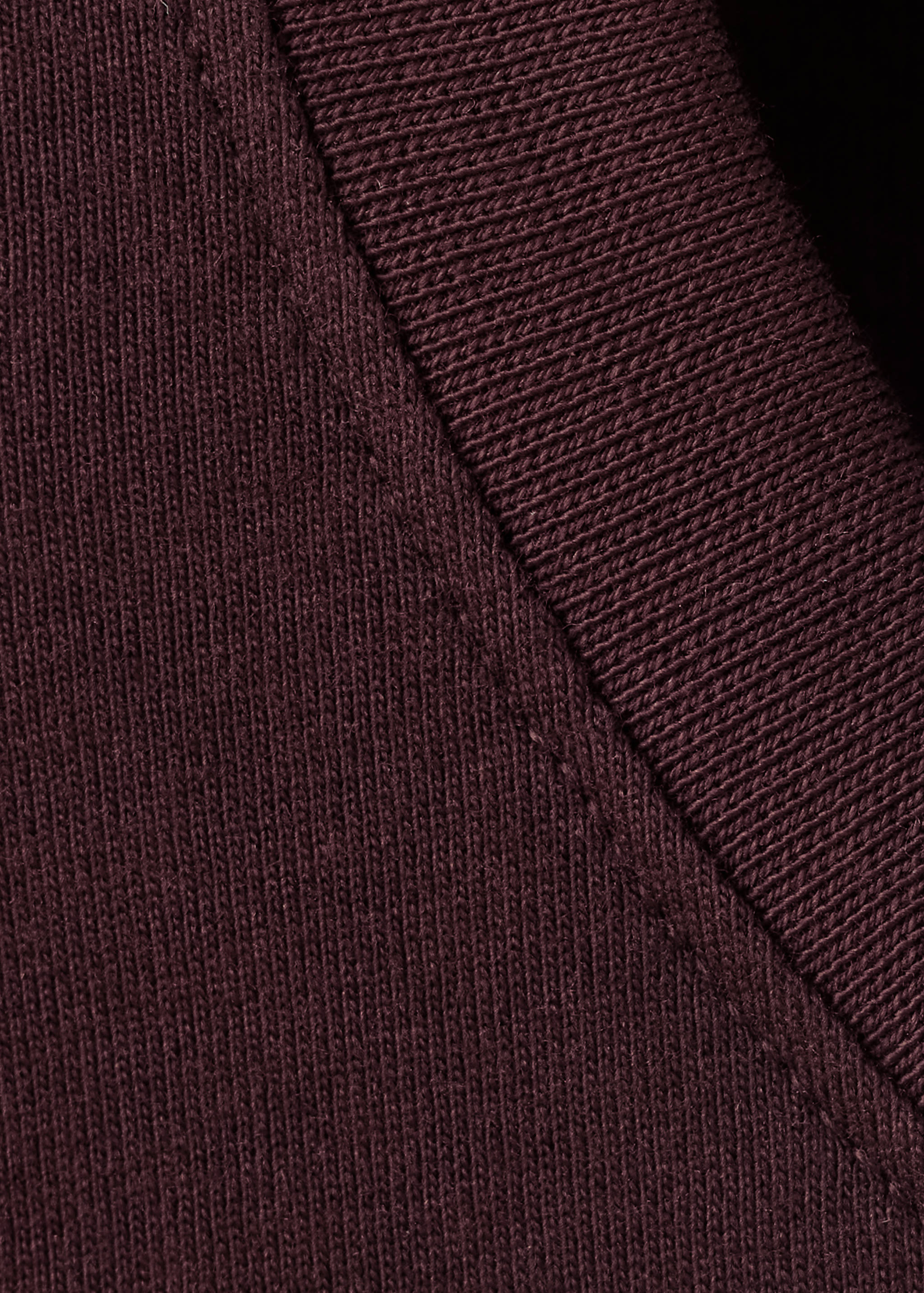 Close-up of the ribbed collar and knit fabric on a dark burgundy t-shirt.