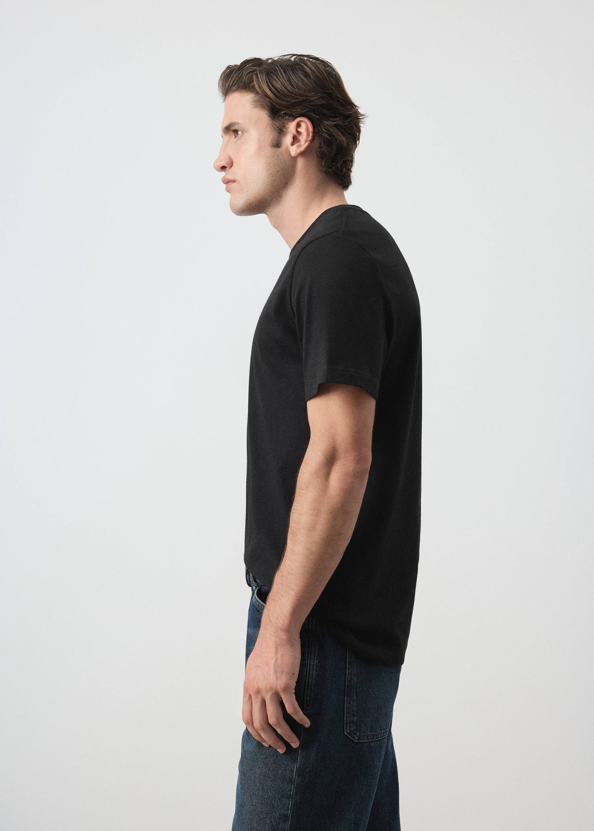Black short-sleeved crew neck t-shirt worn with blue jeans.