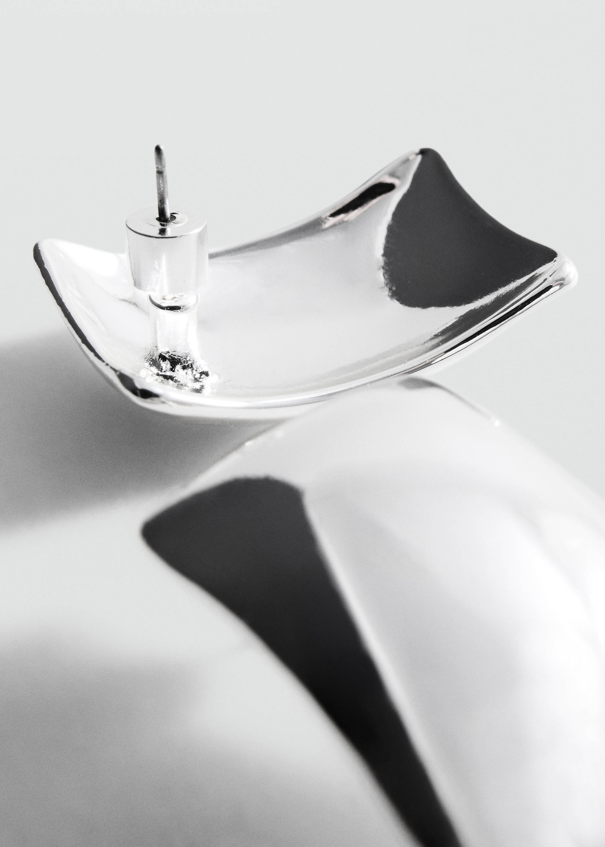 Silver-tone metallic earrings shown in a three-quarter close-up view.