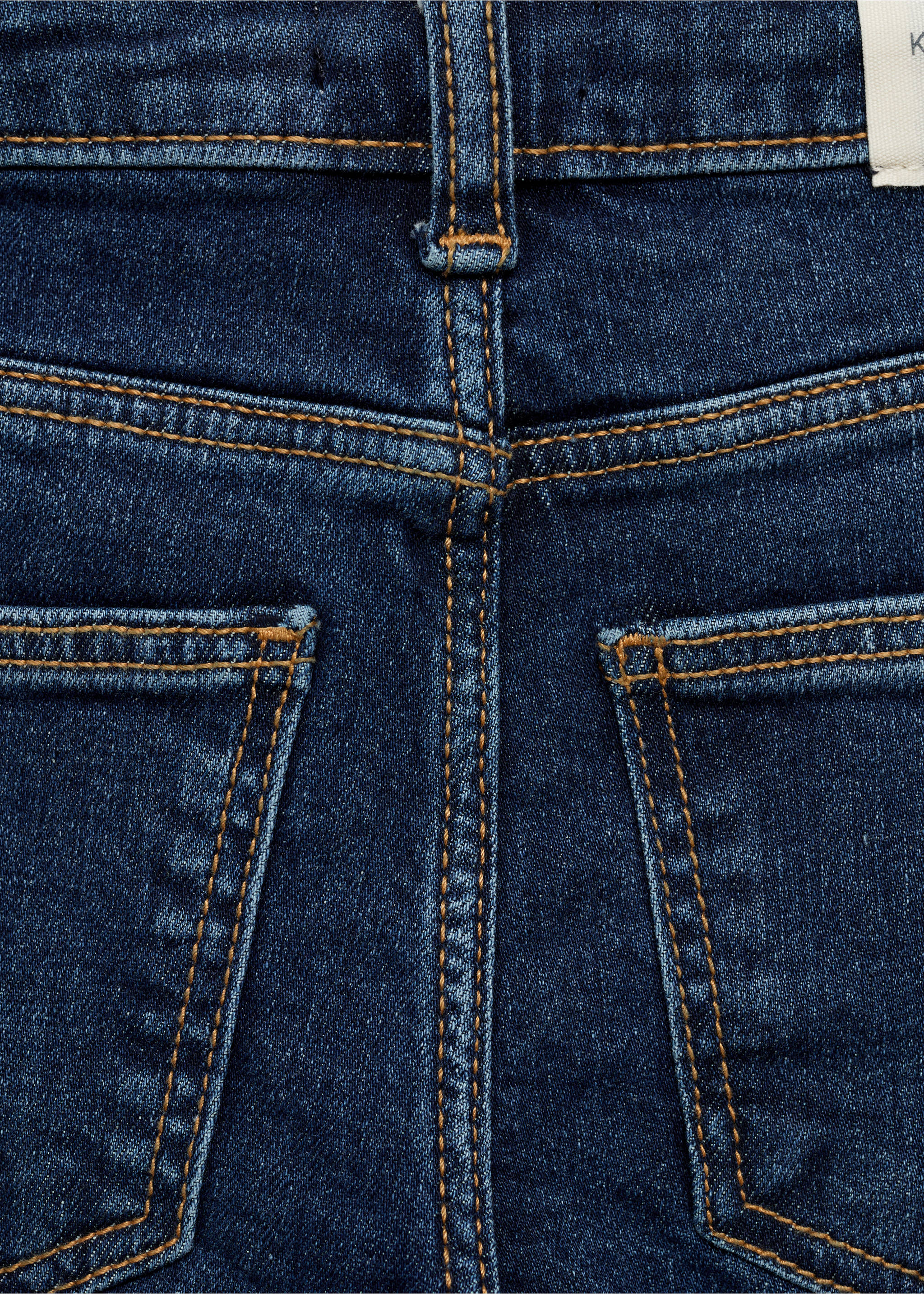 Close-up of dark blue denim trousers back pockets and stitching., Dark Blue. Ref: 77001012-00.
