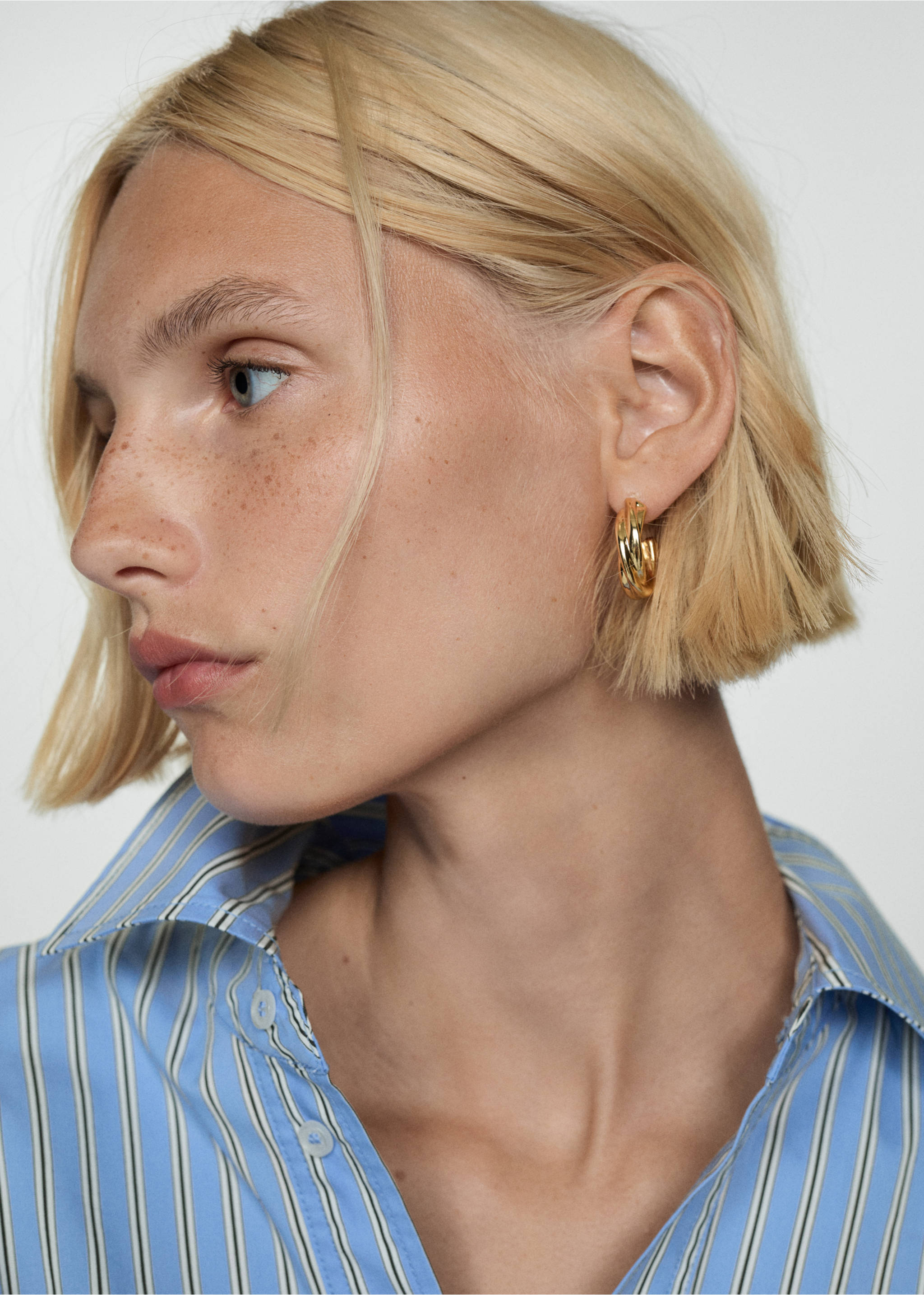 Close-up of a model wearing a striped shirt and gold hoop earring., Blue. Ref: 77044027-00.