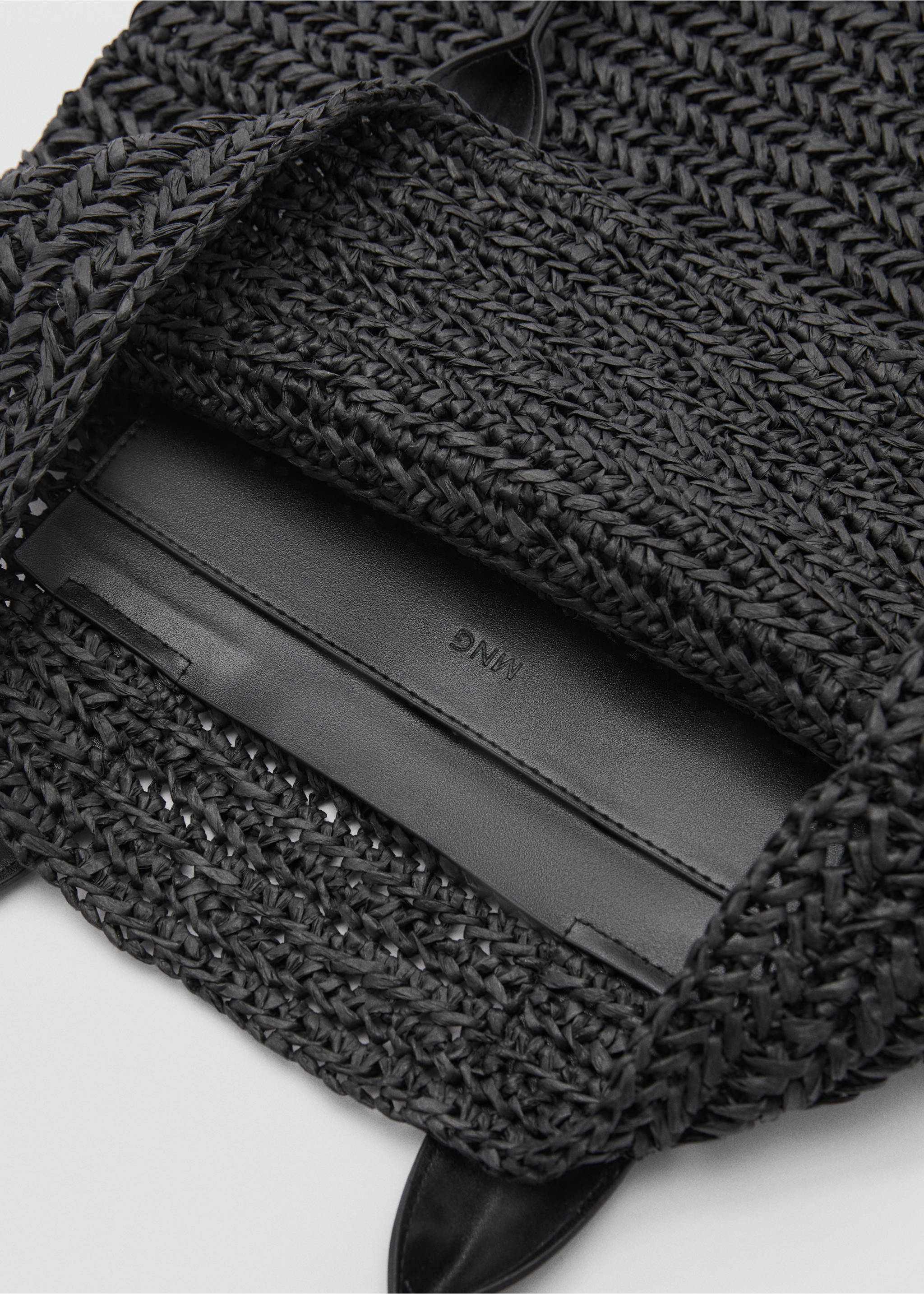 Close-up of a black woven tote bag interior showing the textured weave and branded pocket., Black. Ref: 77050349-00.