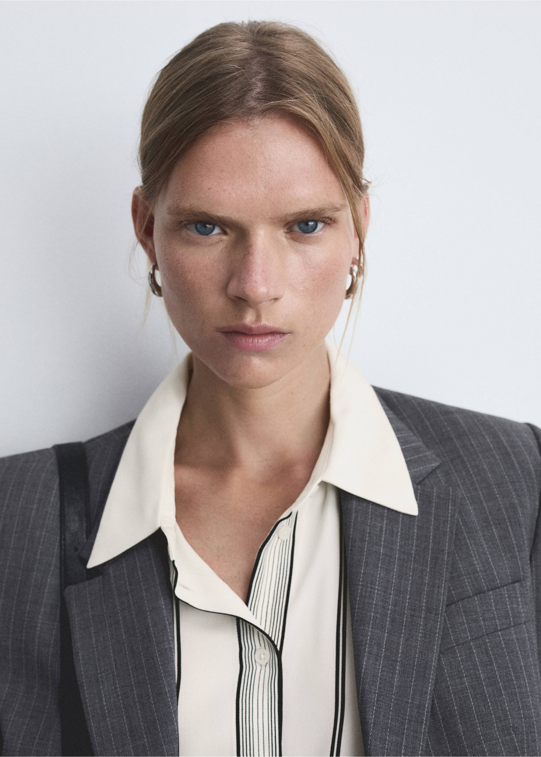 Close-up of a cream pinstripe shirt with a pointed collar, worn under a grey blazer., Off White. Ref: 77055643-00.