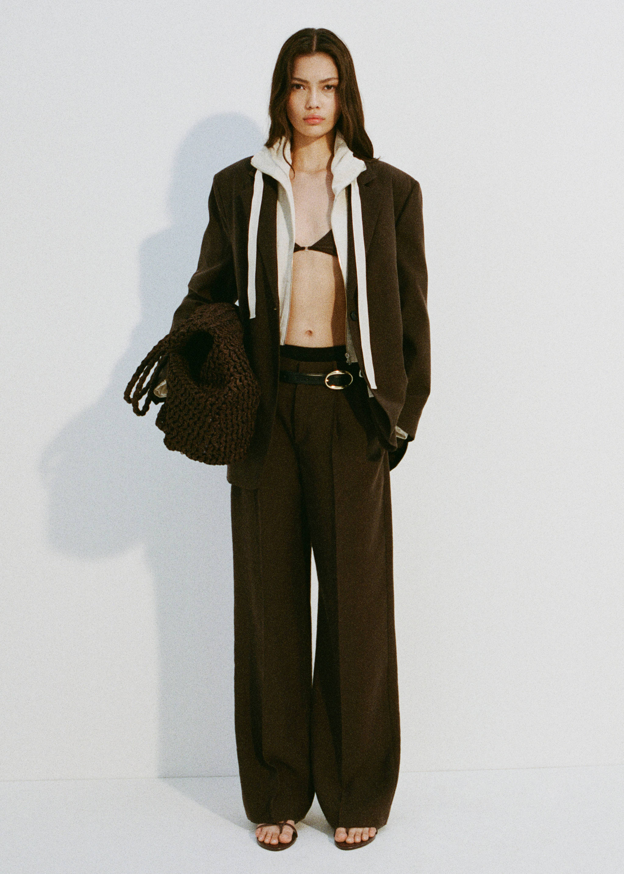 Dark brown woven handbag carried with a matching oversized blazer and trousers outfit, Chocolate. Ref: 87007165-01.