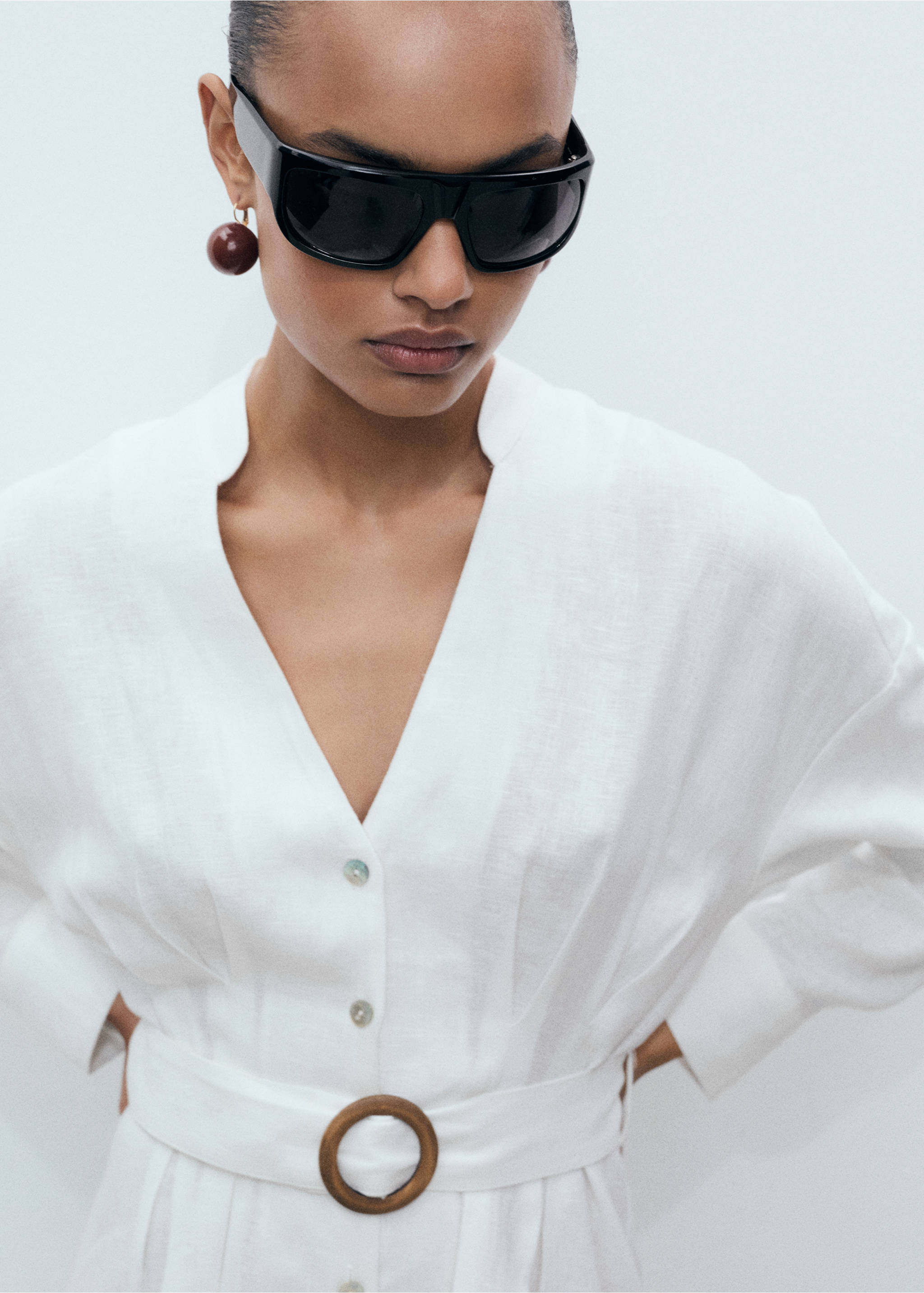 Close-up of a white dress with a V-neck, button front, and round wooden belt buckle., White. Ref: 87017166-00.