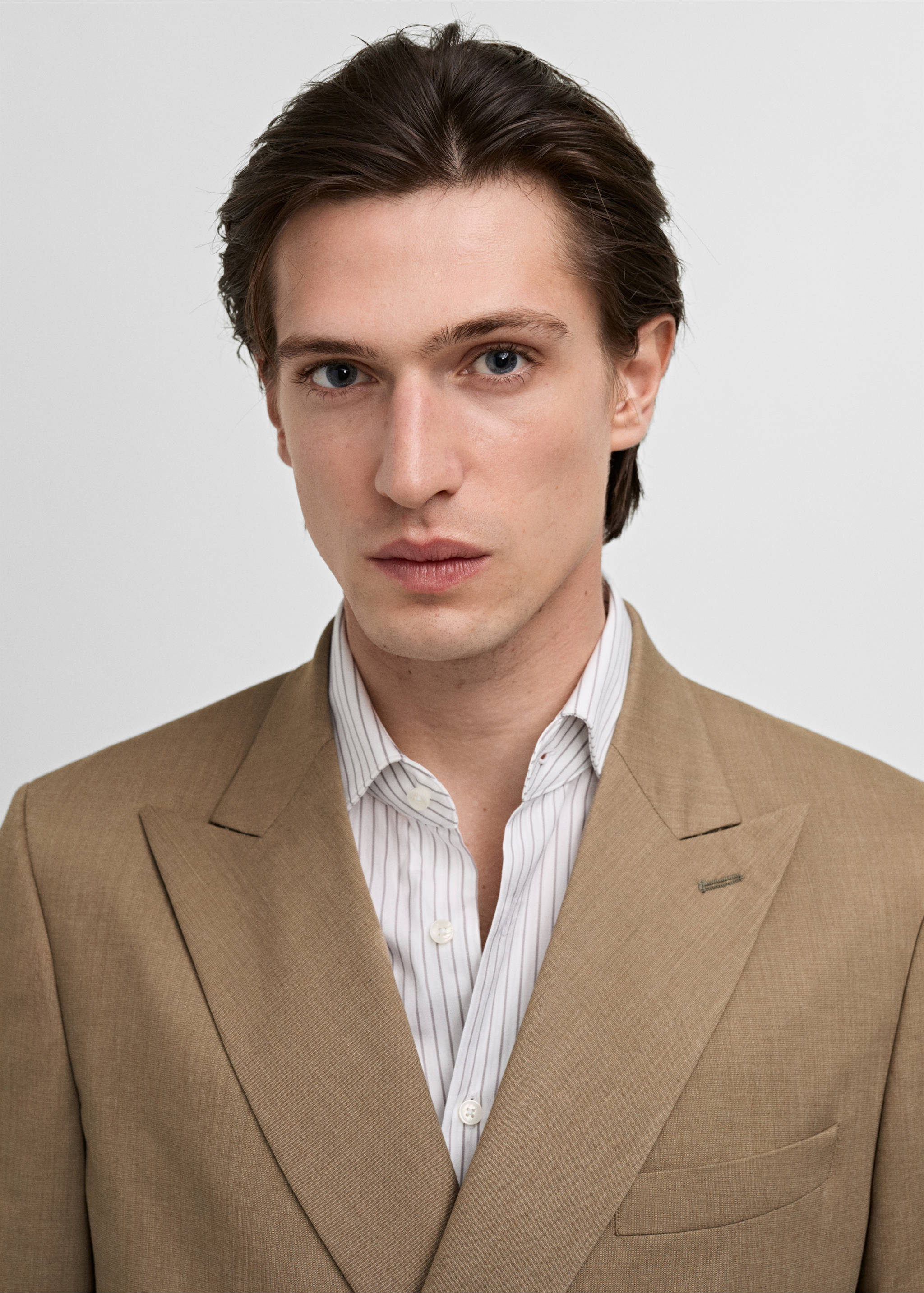 Close-up of a beige blazer with peak lapels, worn over a striped shirt., Medium Brown. Ref: 87025929-00.