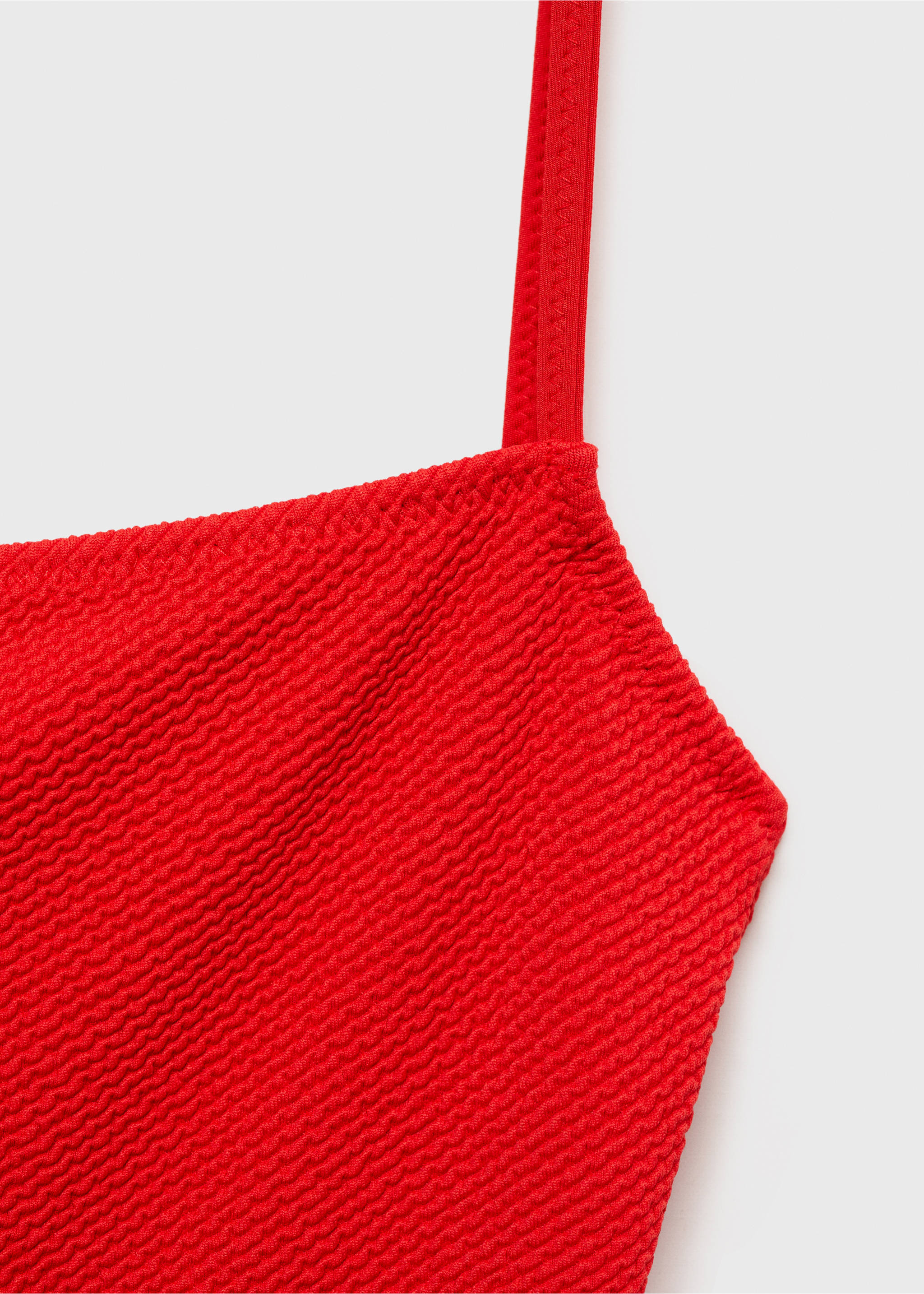 Close-up of a textured red swimsuit strap and bodice detail., Red. Ref: 87035956-00.