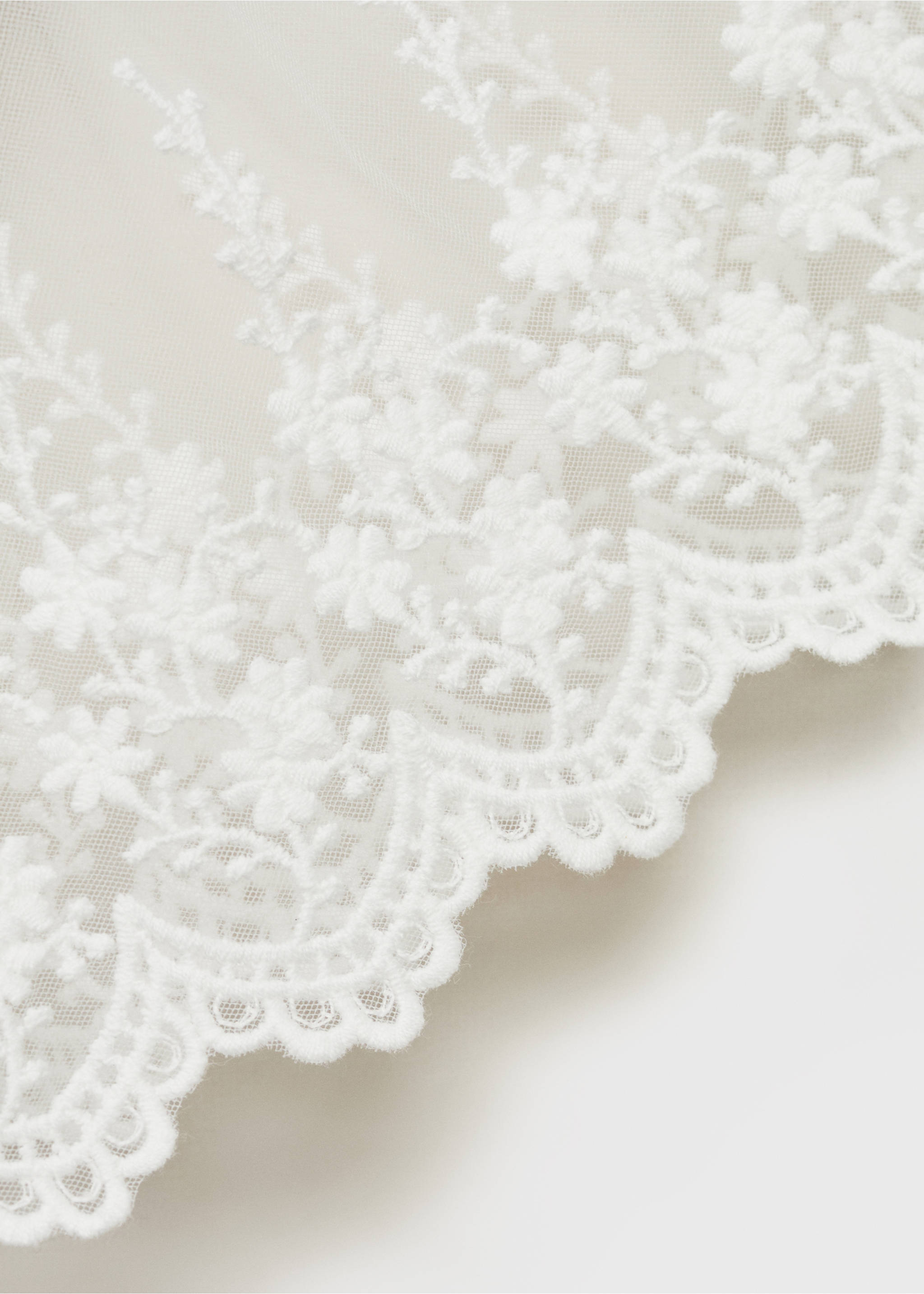 Close-up of a white dress showing sheer tulle with floral embroidery and a scalloped hem., White. Ref: 87053635-01.
