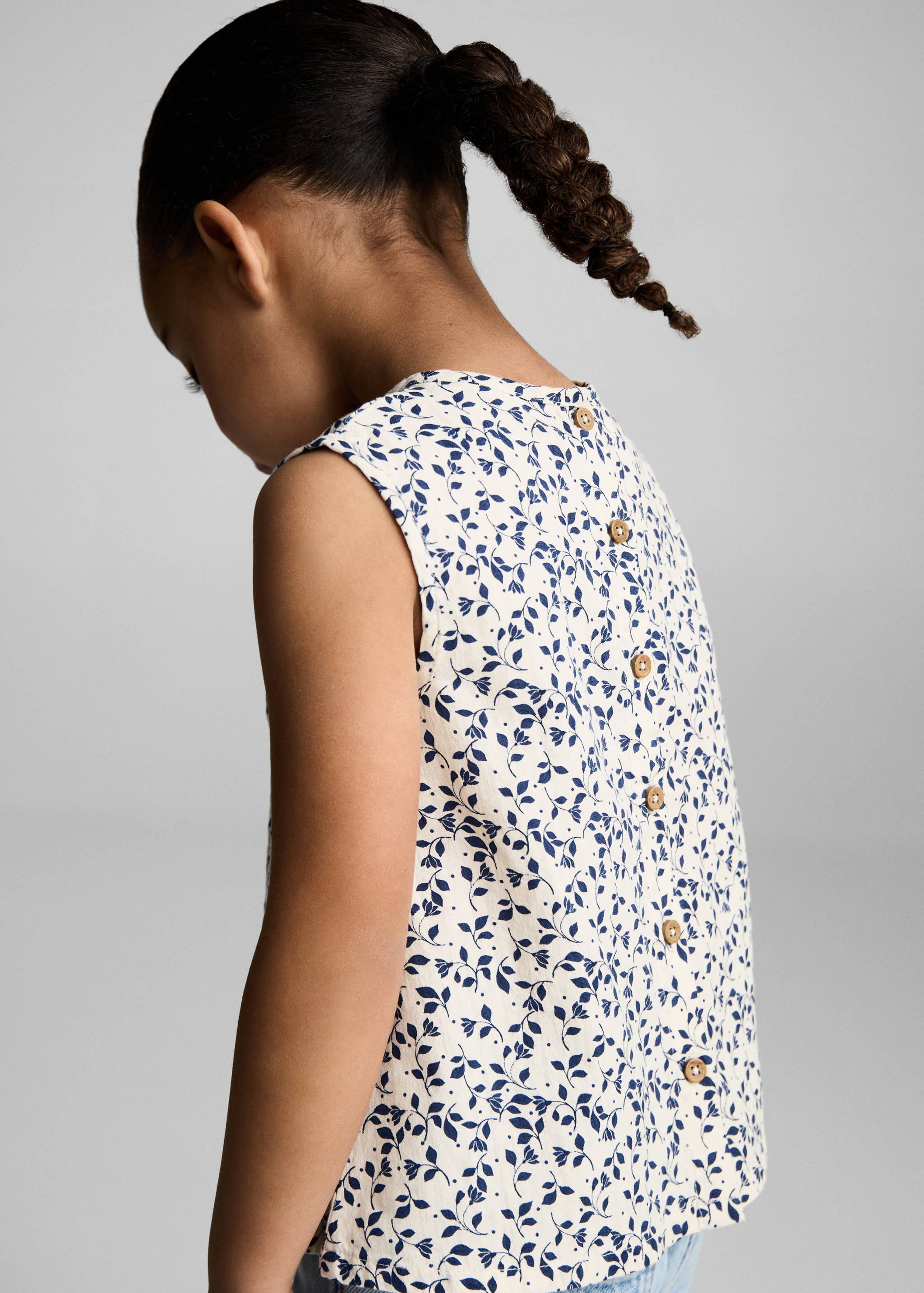 Back view of a cream and blue printed blouse with wooden back buttons.