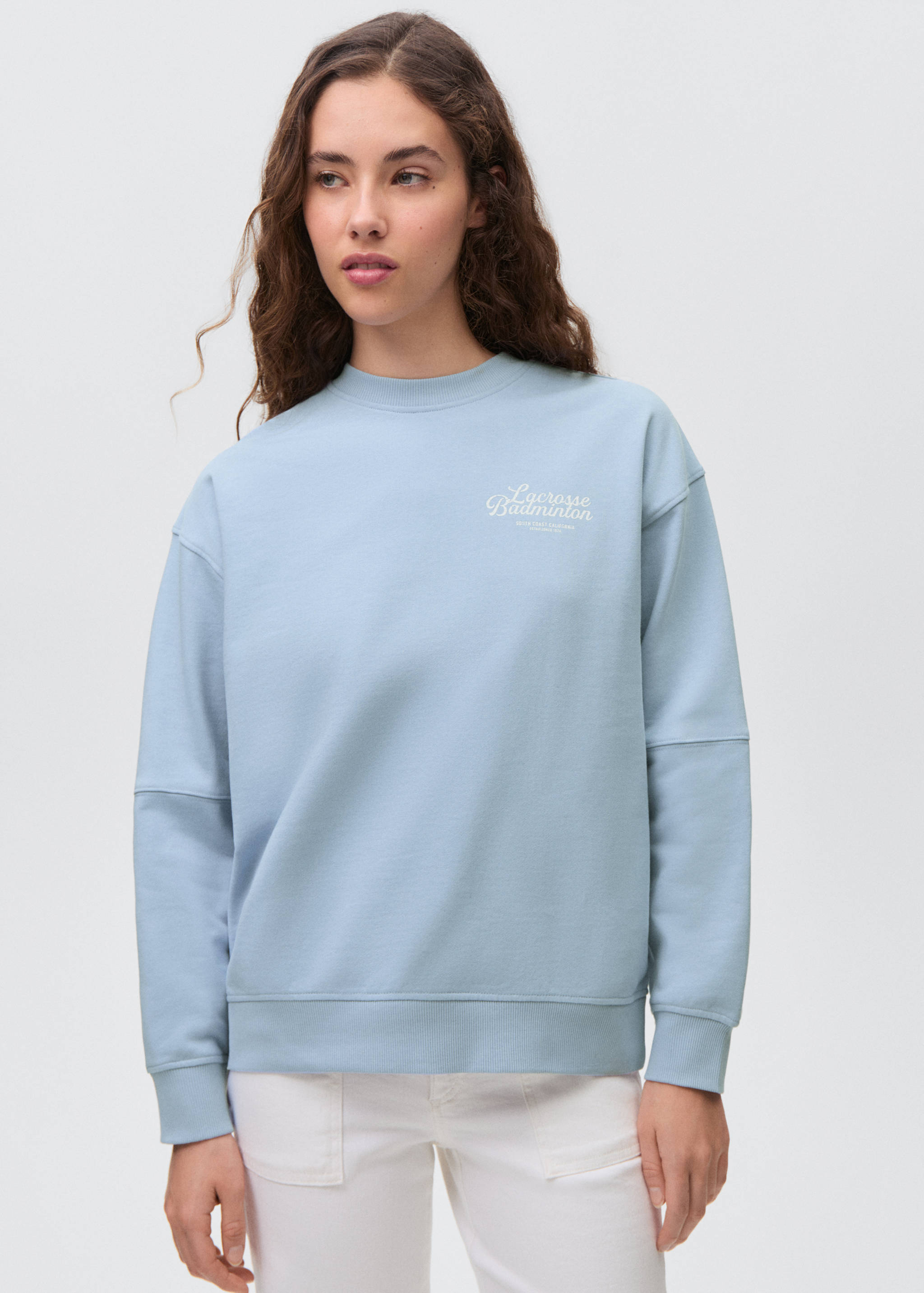 Light blue crew-neck sweatshirt with long dropped-shoulder sleeves and a small chest graphic.
