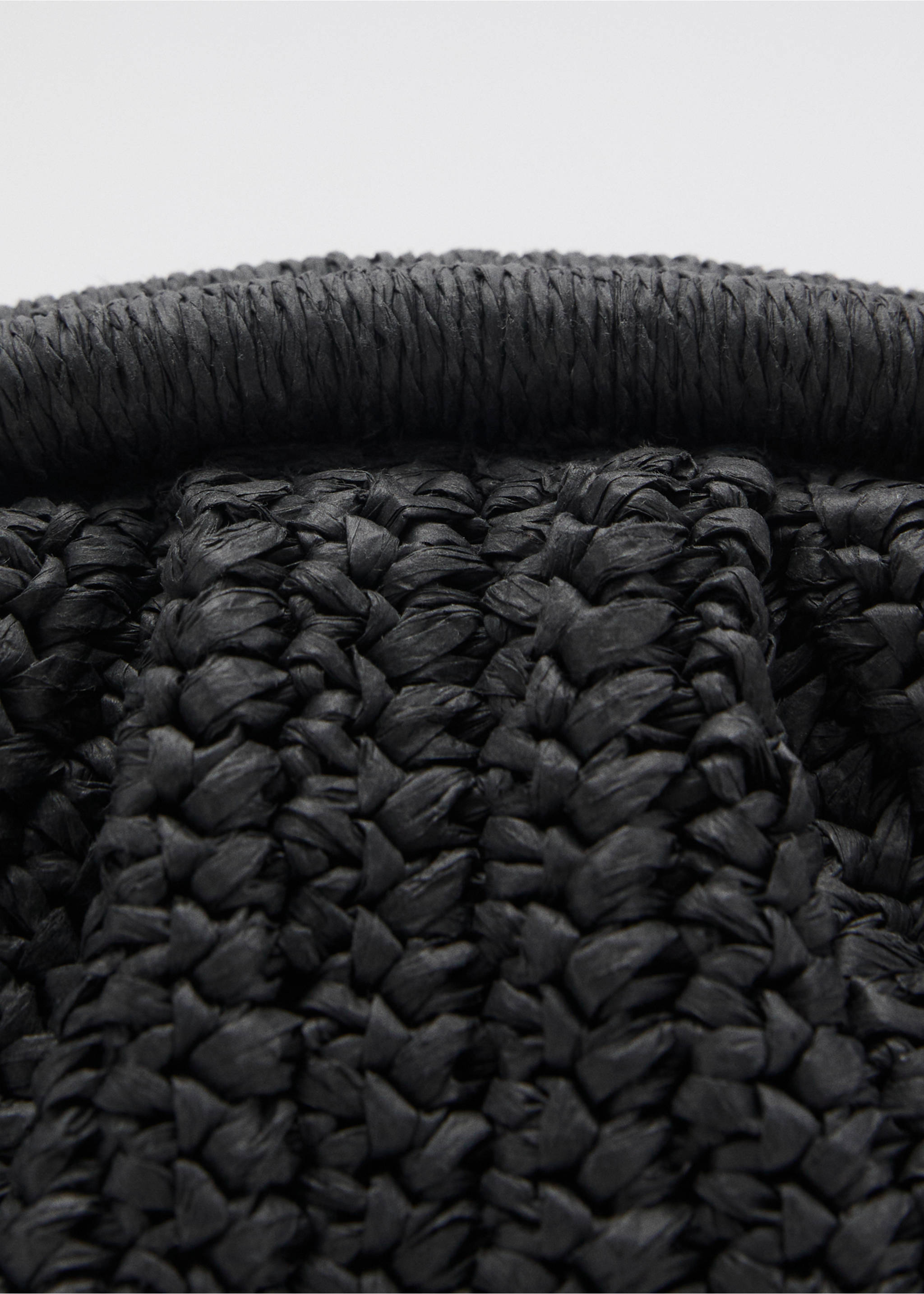 Close-up of a black woven cross-body bag showing its textured material and rounded rim., Black. Ref: 87065921-00.