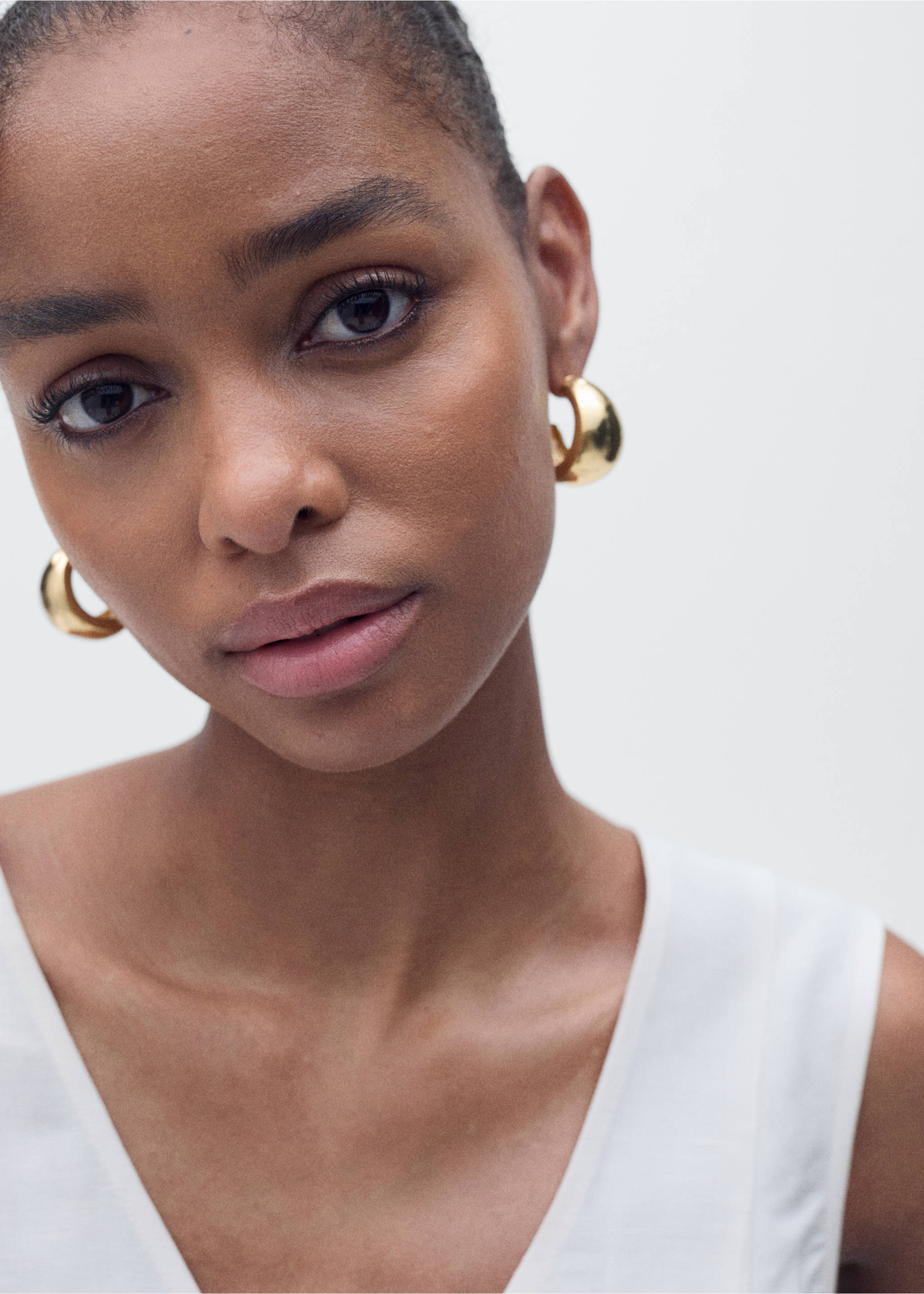 Close-up of a model wearing a white V-neck sleeveless top., Ecru. Ref: 87067179-00.