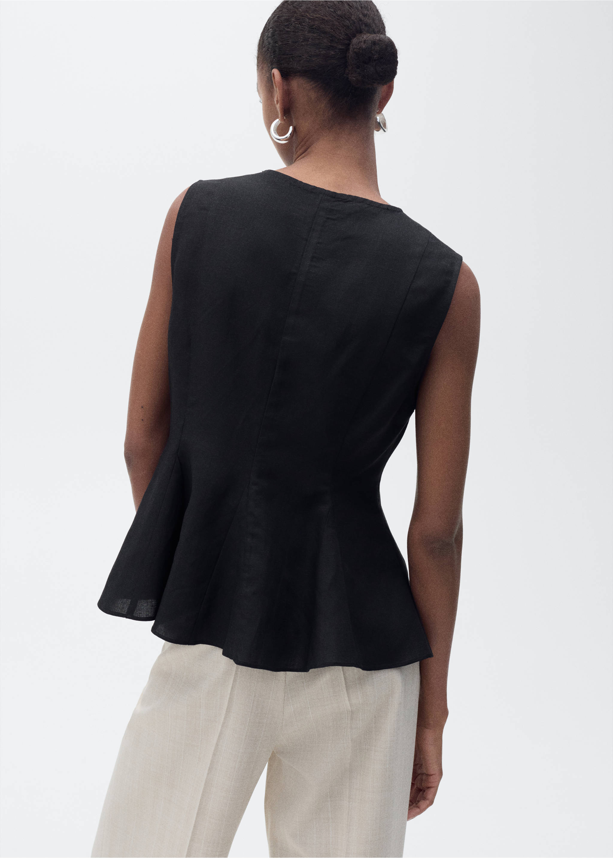 Black sleeveless peplum top seen from the back, paired with light trousers., Black. Ref: 87067179-00.