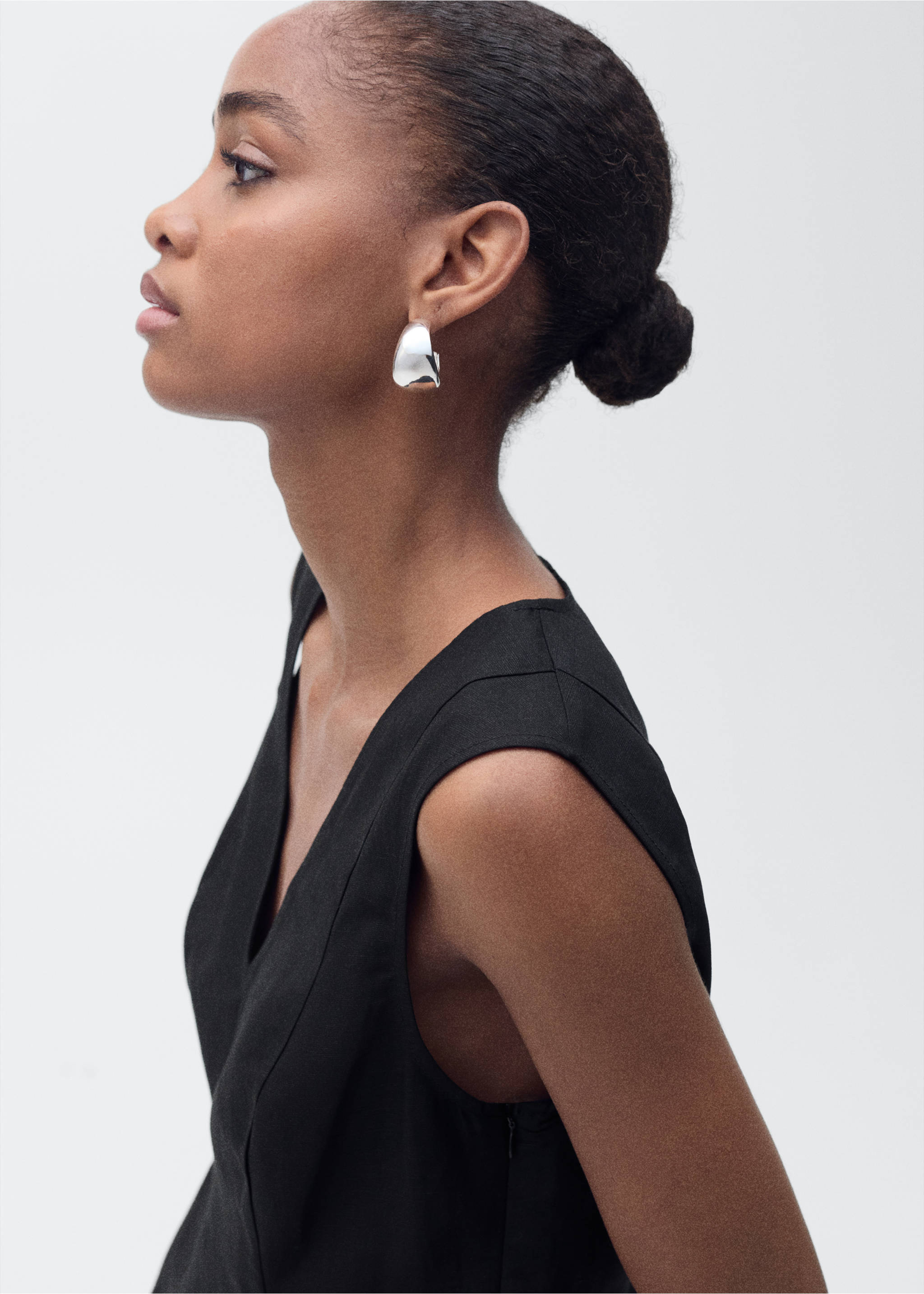 Black sleeveless V-neck top with panel seams, shown in a close-up profile view., Black. Ref: 87067179-00.