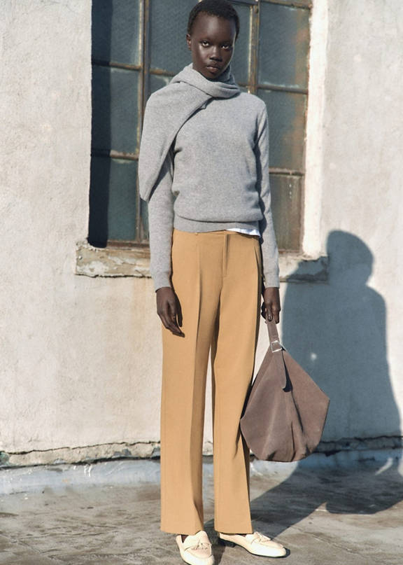 Woman wearing beige trousers and a brown oversized jumper.