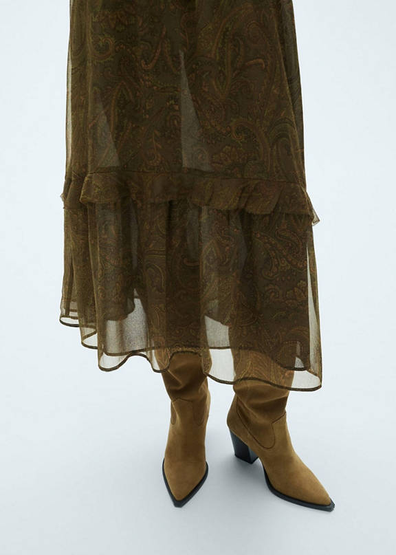 Woman wearing an outfit with cowboy boots and a long dress