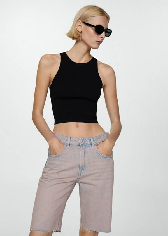 Girl wearing a festival outfit with ripped denim shorts and a black top.