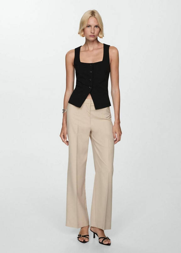 Woman combining beige wideleg trousers with a white jumper.