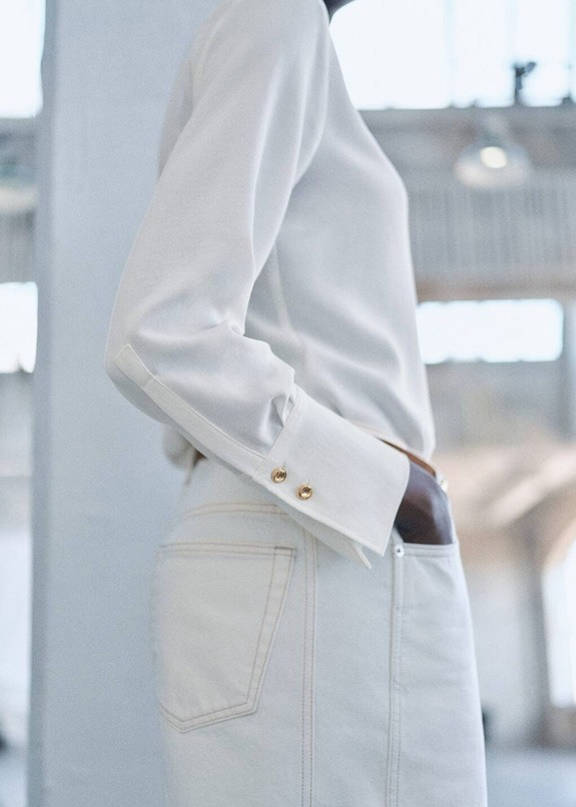 A woman combining jeans with a beige jacket.